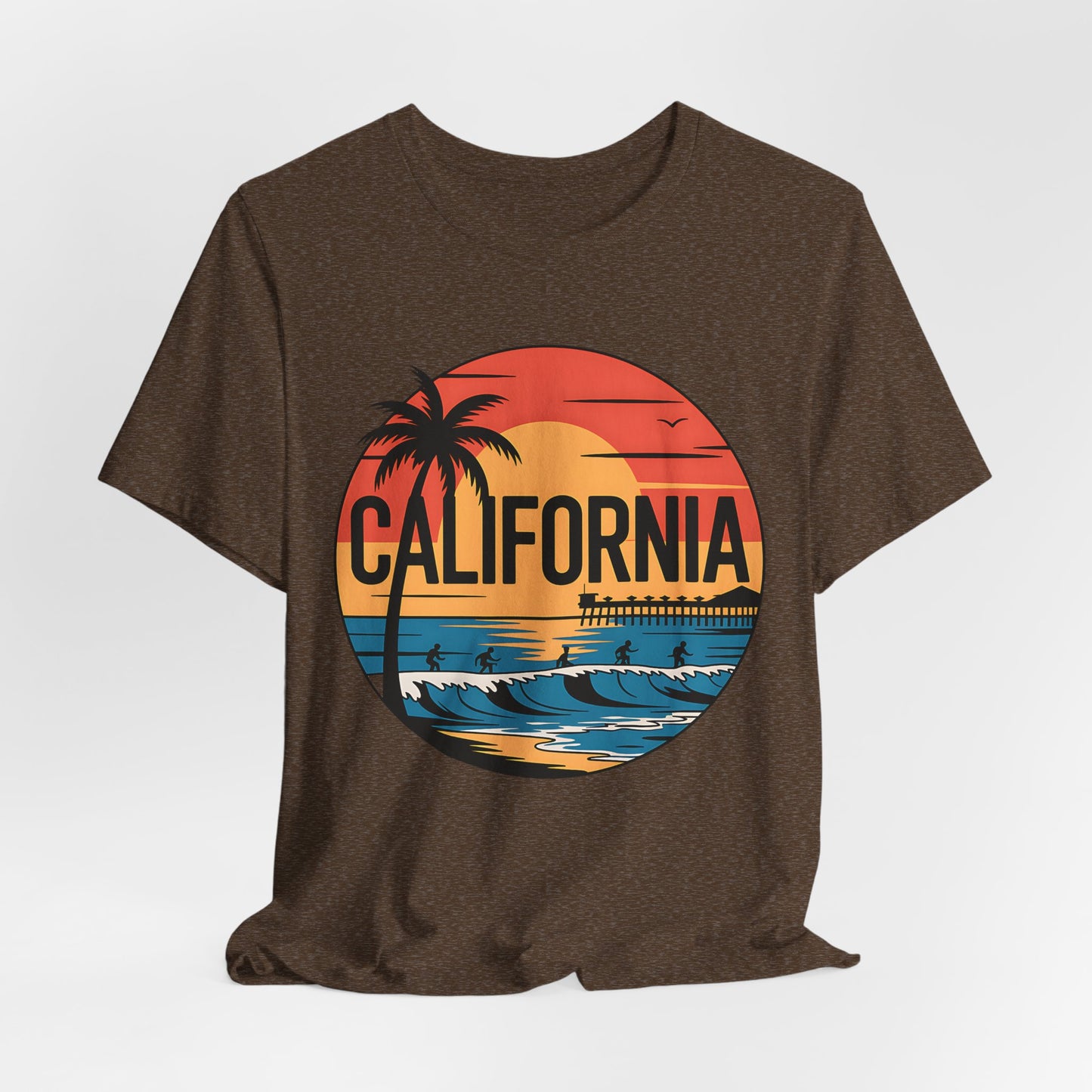 The California Sunset Graphic T-Shirt is a brown unisex jersey tee featuring a circular beach sunset design with palm tree, pier, surfers, waves, and bold California text—perfect for your summer wardrobe.