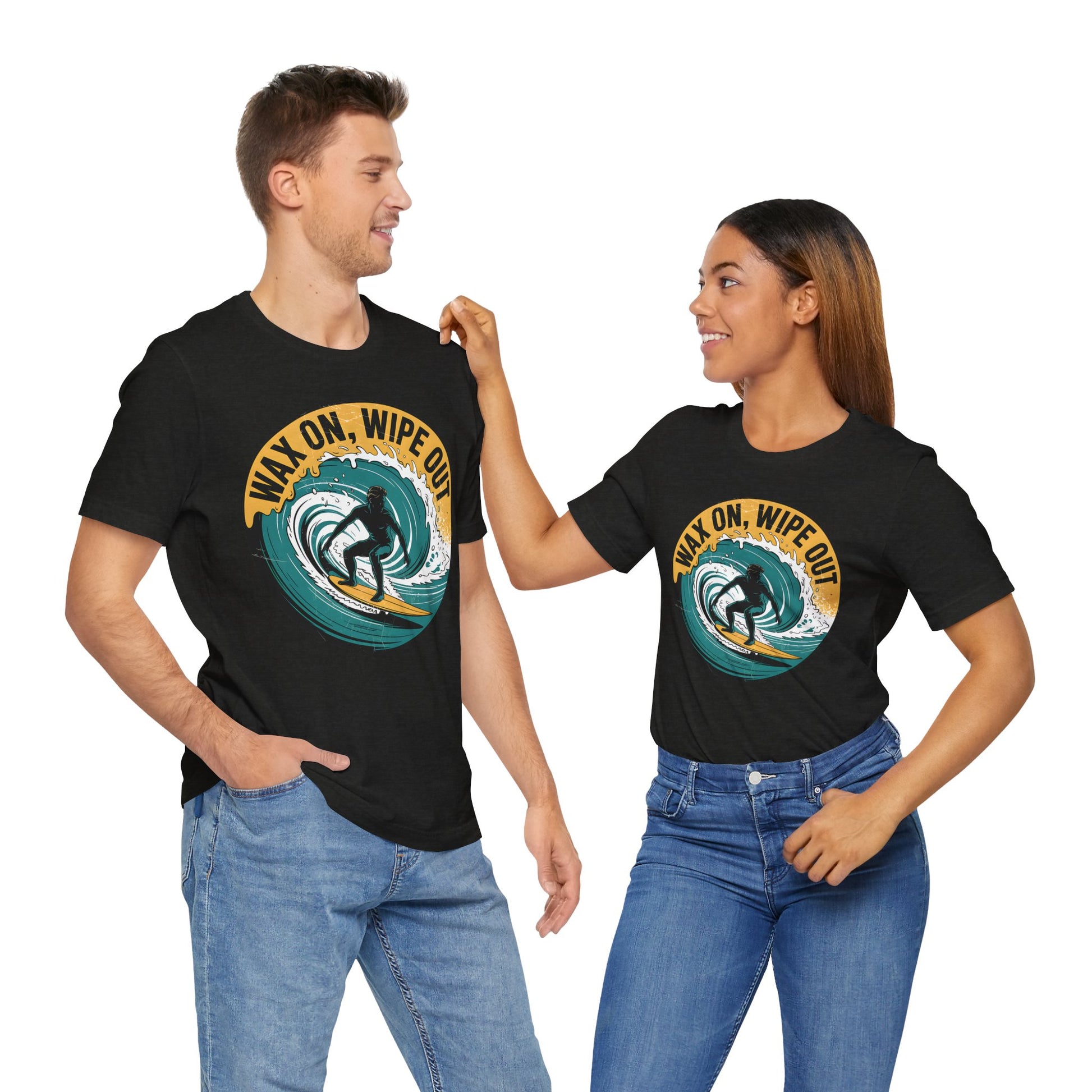 A smiling couple wears matching Surfing Inspired Unisex Short Sleeve T-Shirts—Wax On, Wipe Out—with a surfing graphic, hands in jeans pockets. The womans hand rests on his shoulder. Perfect for surf fans.
