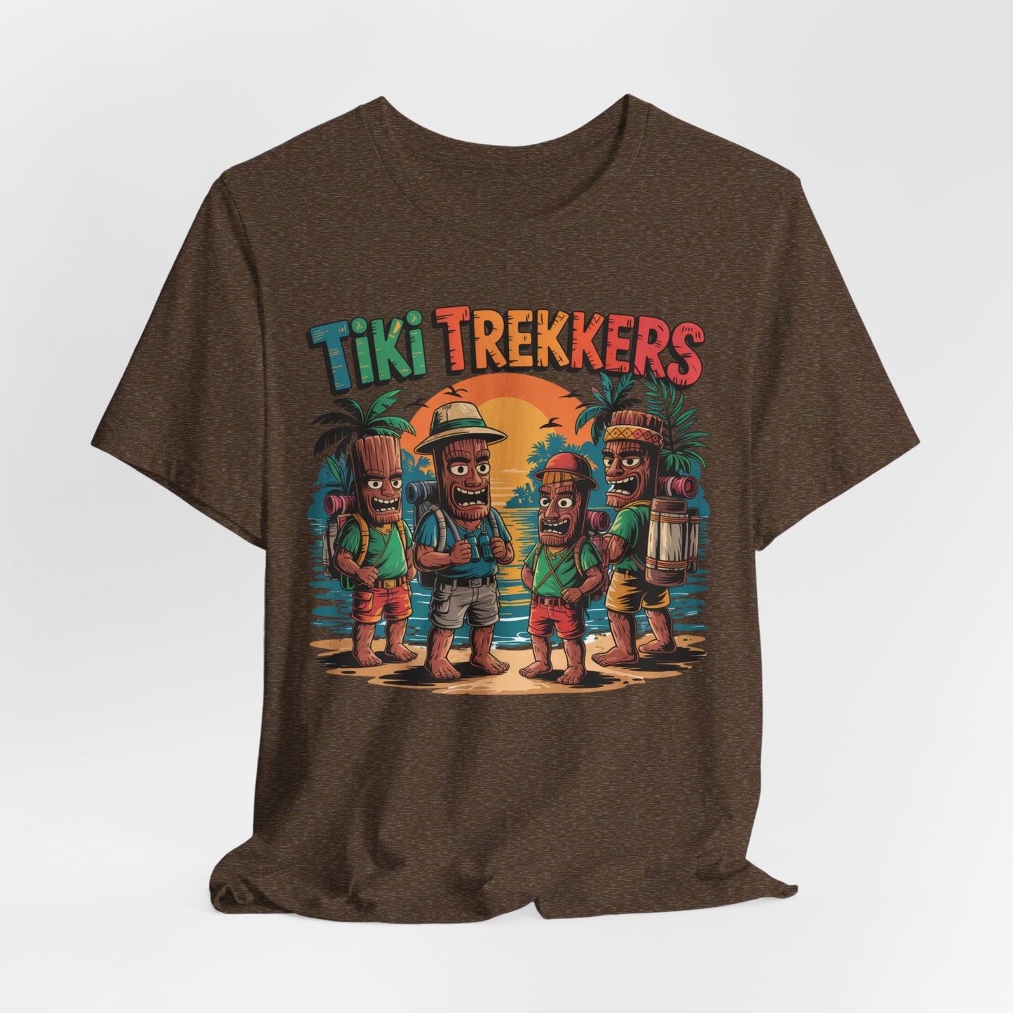 The Tiki Trekkers Graphic Tiki T-Shirt is a unisex jersey tee with a vibrant cartoon of four tiki characters in hiking gear on a sunset beach, Tiki Trekkers above—ideal for adventure lovers and outdoor fans.