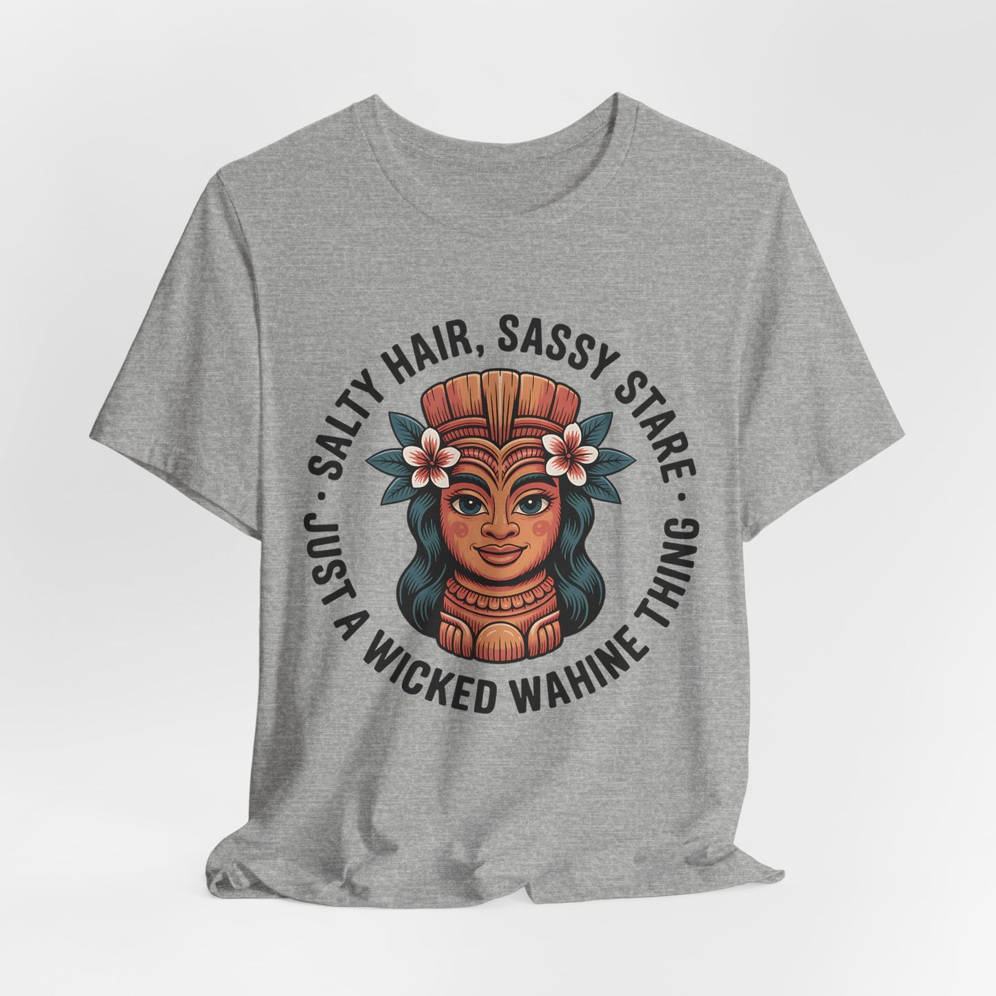 The Wicked Wahine Graphic T-Shirt - Salty Hair, Sassy Stare T-Shirt is a gray unisex tee with an illustrated woman in a headdress and flowers, plus the phrase: Salty Hair, Sassy Stare—perfect for beach lovers and outdoor adventures.