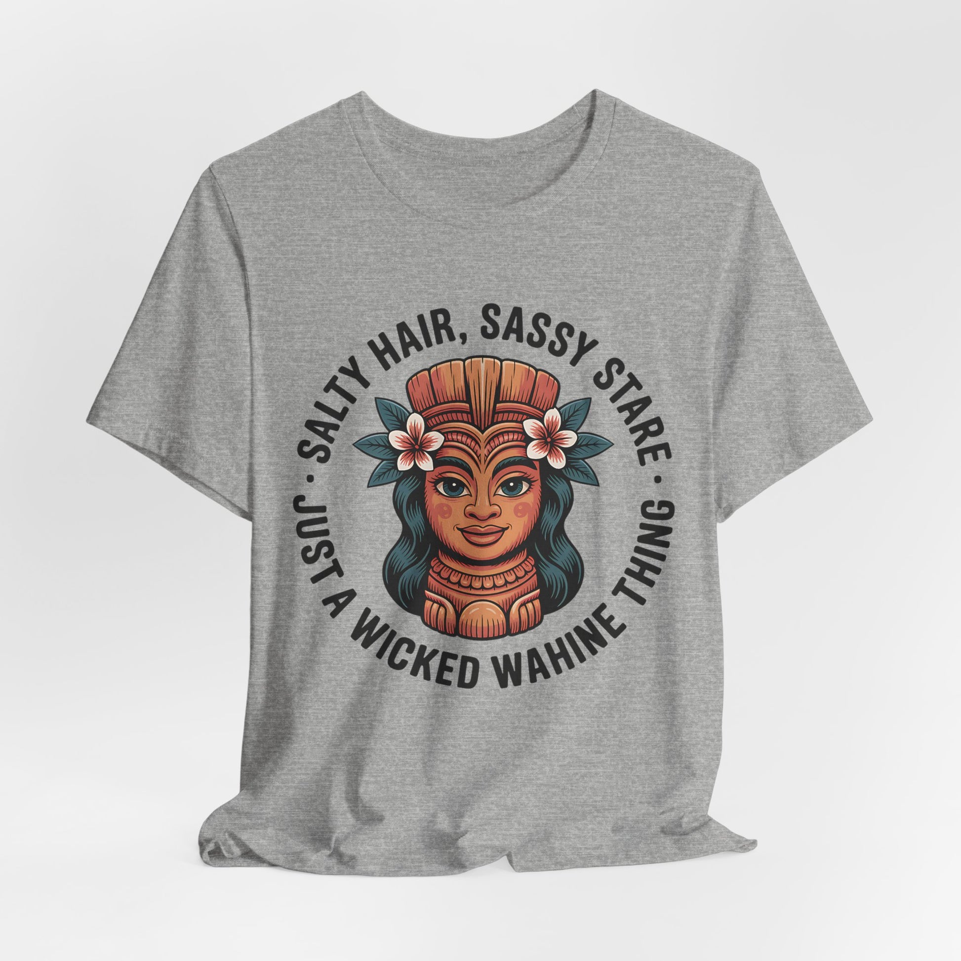 The Wicked Wahine Graphic T-Shirt - Salty Hair, Sassy Stare T-Shirt is a gray unisex tee with an illustrated woman in a headdress and flowers, plus the phrase: Salty Hair, Sassy Stare—perfect for beach lovers and outdoor adventures.