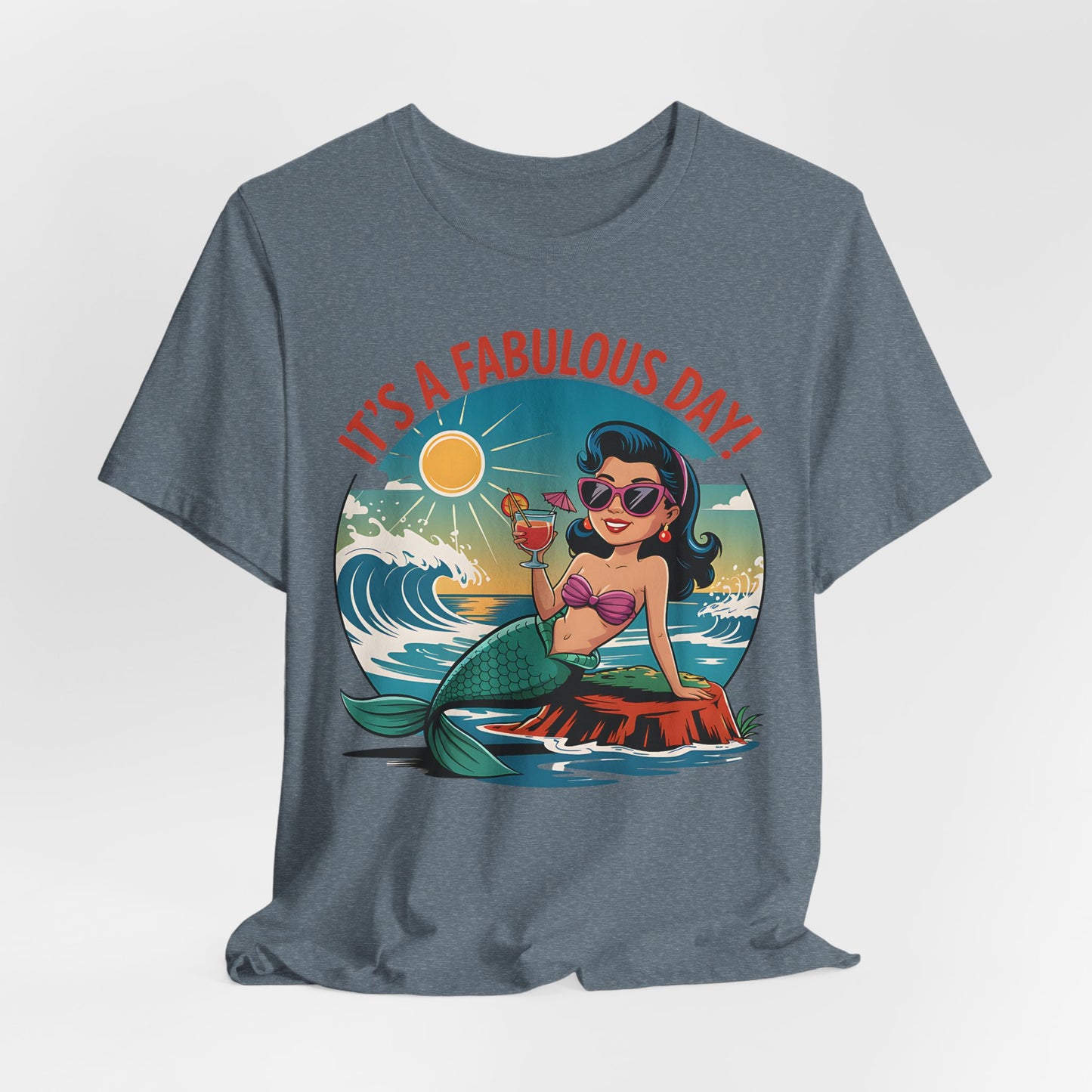 The Fabulous Day Mermaid Unisex Tee is blue and features a cartoon mermaid with sunglasses eating ice cream on a rock, sun and waves around her. Bold red text above reads ITS A FABULOUS DAY!—ideal for fantasy-themed events.