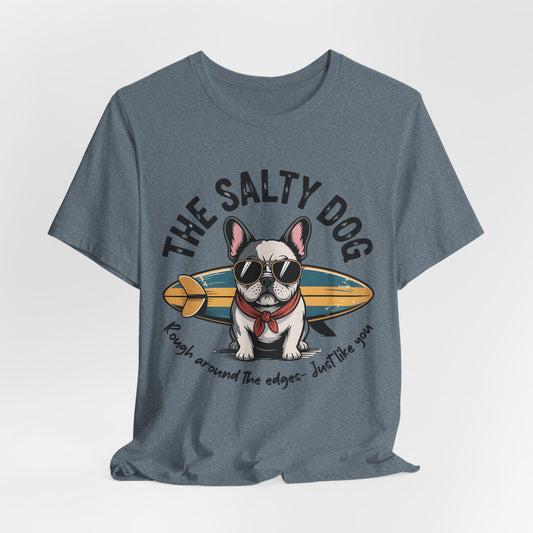 The Salty Dog Unisex Surf T-Shirt is a blue tee with a French Bulldog in sunglasses and a red bandana by a surfboard. It reads THE SALTY DOG and Rough around the edges – just like you. Perfect for beach lovers.