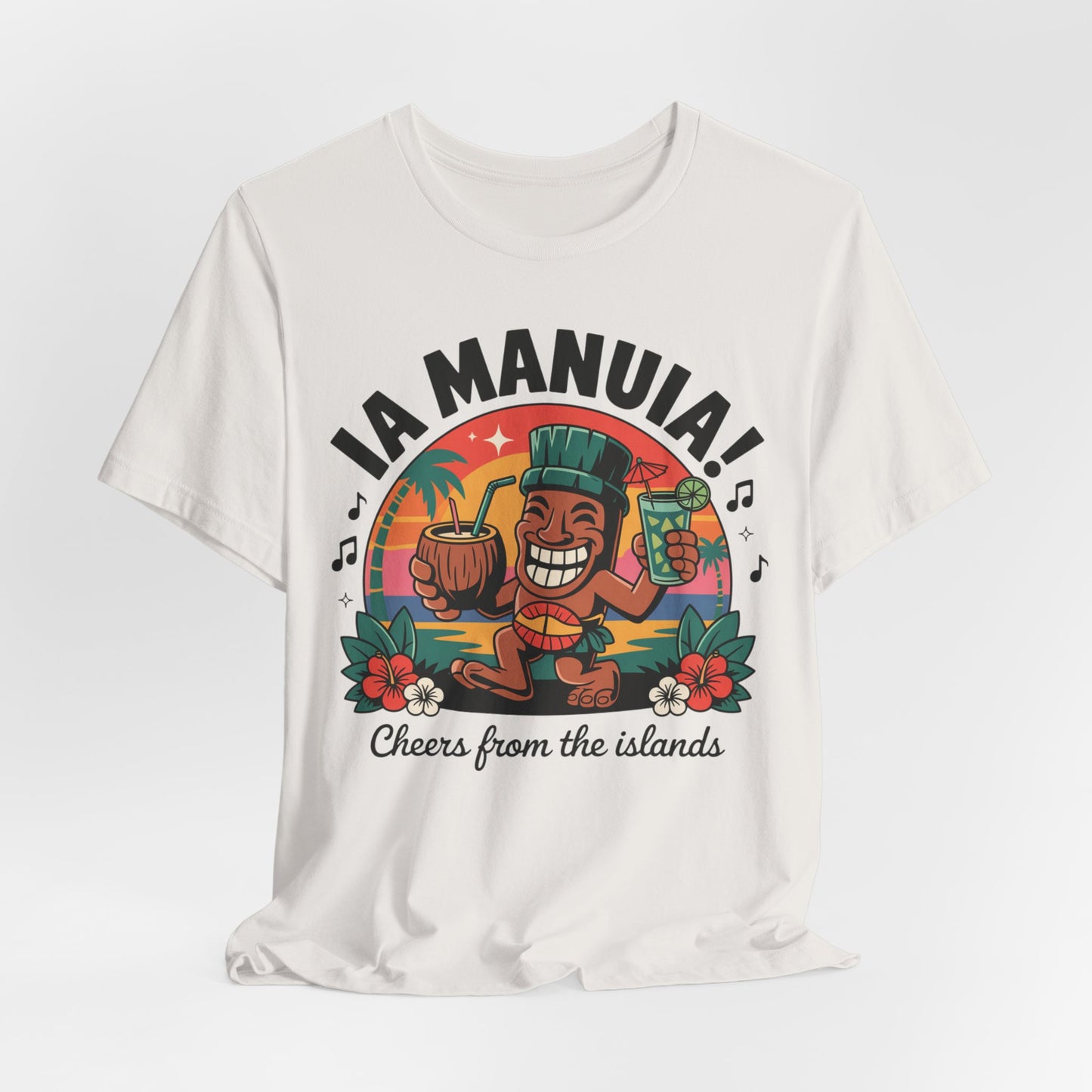 The IA MANUIA! Island Vibes Unisex Jersey Tiki T-Shirt features a smiling islander with a coconut drink, flowers, sunset, musical notes, and “IA MANUIA!” and “Cheers from the islands” text—ideal for tropical themed events.