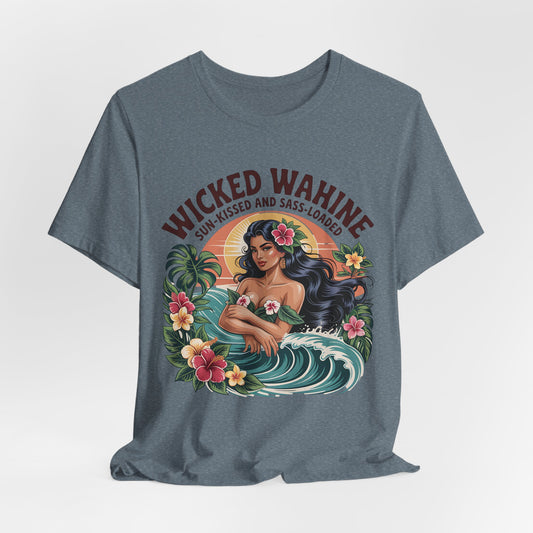 The Wicked Wahine Graphic T-Shirt – Sun-Kissed and Sass-Laden Unisex Jersey features a blue tee with a woman with long dark hair, flowers, tropical designs, and wave. Text: “WICKED WAHINE” above and “SUN-KISSED AND SASS-LOADED” below.