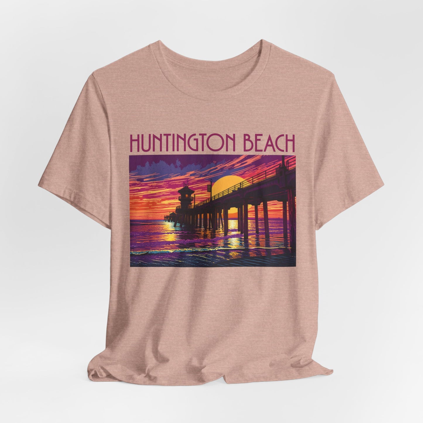 The Huntington Beach Sunset T-Shirt is a beige unisex jersey short sleeve tee with a vibrant sunset pier graphic and Huntington Beach in bold—ideal for fans of classic beach vibes.