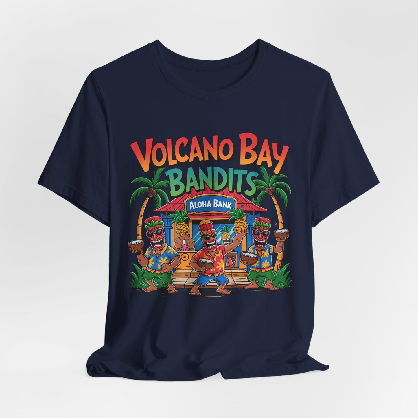 The Volcano Bay Bandits Graphic Tiki T-Shirt is a unisex navy short sleeve shirt featuring Volcano Bay Bandits above cartoon tiki dancers, a tropical hut labeled Aloha Bank, and palm trees—ideal for casual or adventure wear.