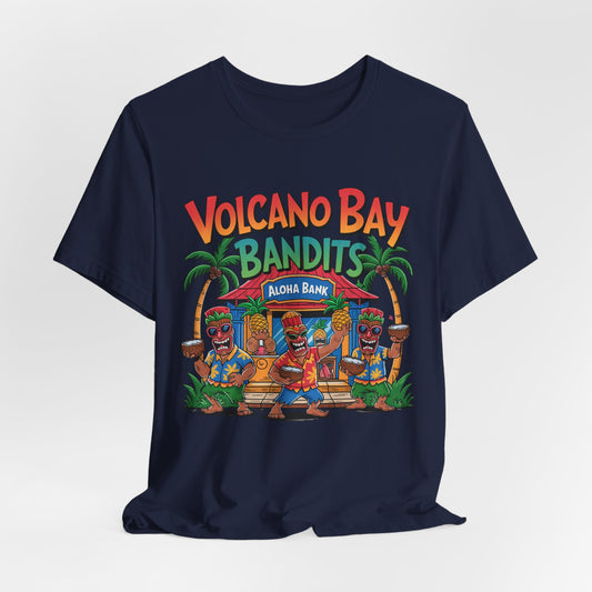 The Volcano Bay Bandits Graphic Tiki T-Shirt is a unisex navy short sleeve shirt featuring Volcano Bay Bandits above cartoon tiki dancers, a tropical hut labeled Aloha Bank, and palm trees—ideal for casual or adventure wear.