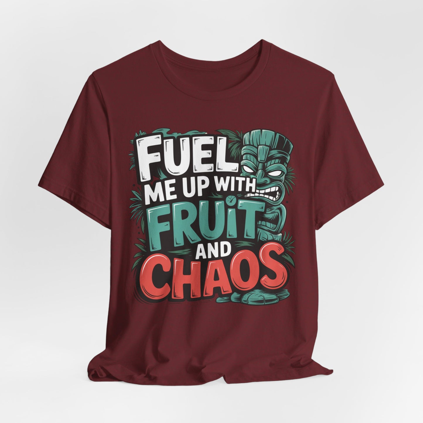 The Fuel Me Up With Fruit and Chaos Unisex Jersey Tiki T-Shirt features a playful cartoon tiki face, vibrant leaves, and bold lettering—perfect for adding fun to your summer adventures.