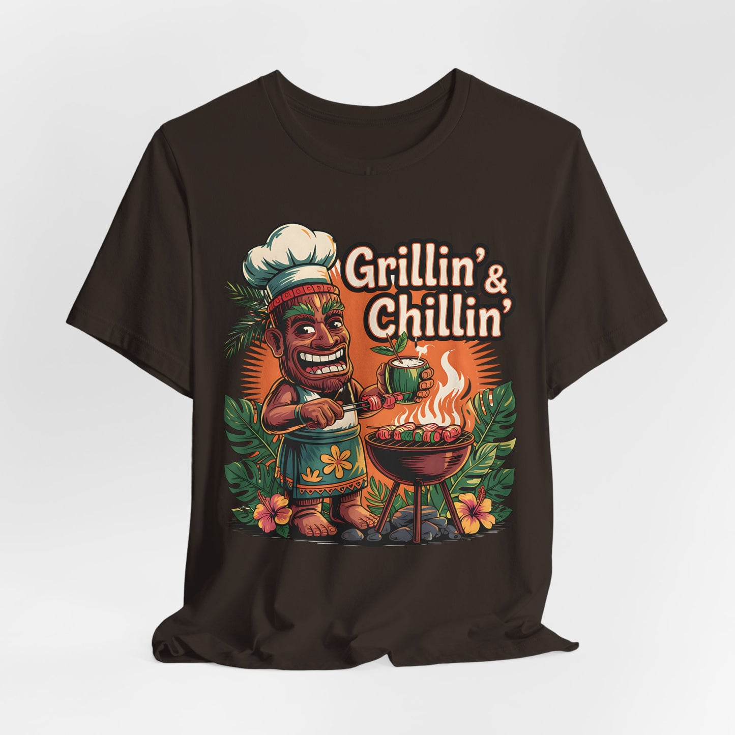 The Grilln & Chilln Unisex Jersey Tiki T-shirt features a cartoon tiki chef grilling with flames and tropical plants, plus Grillin & Chillin text—perfect for Summer BBQs or Luau parties.