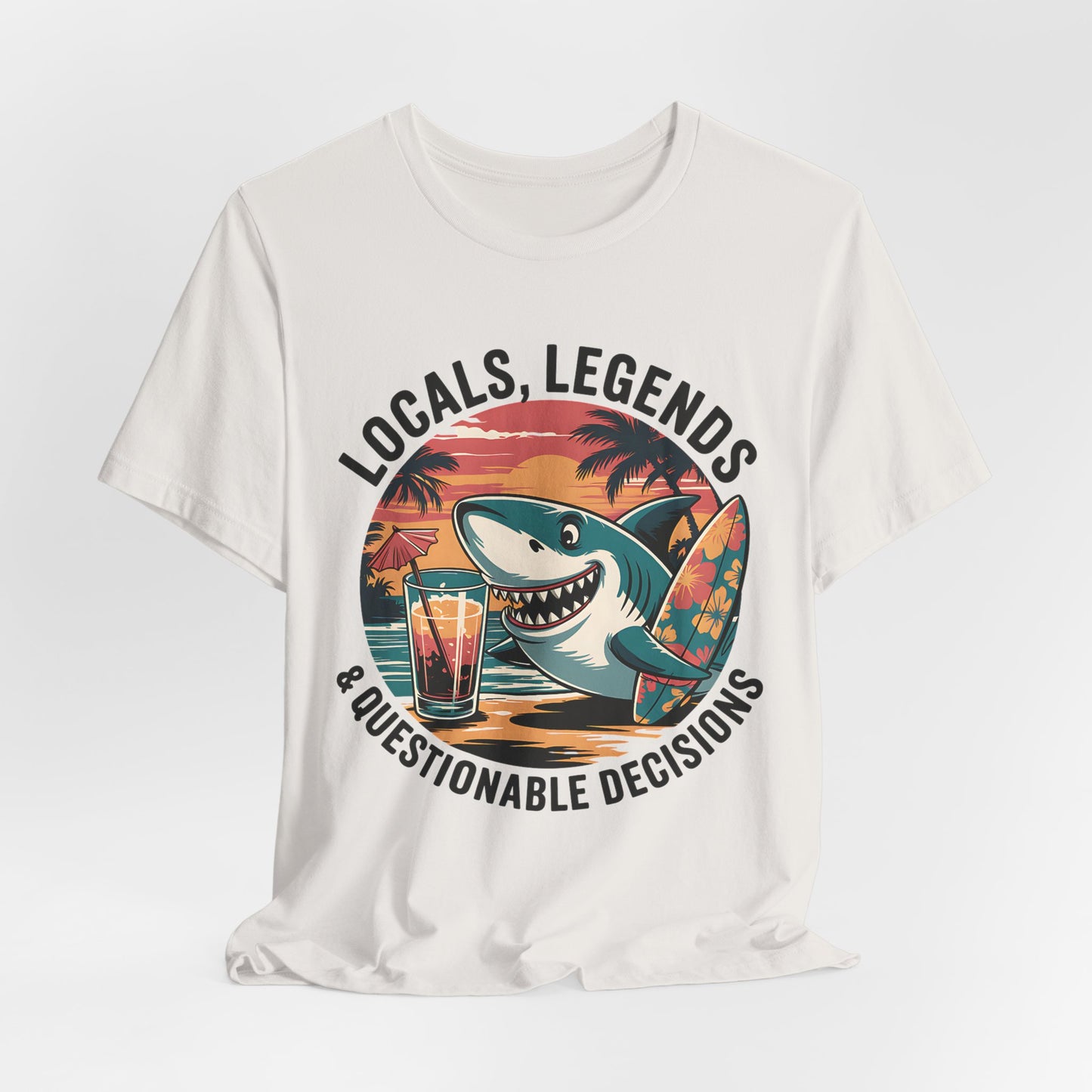 The Funny Shark Graphic T-Shirt - Locals, Legends & Questionable Decisions is a white unisex tee with a cartoon shark, surfboard, drink, palm trees, and sunset—perfect for beach lovers or summer festivals.