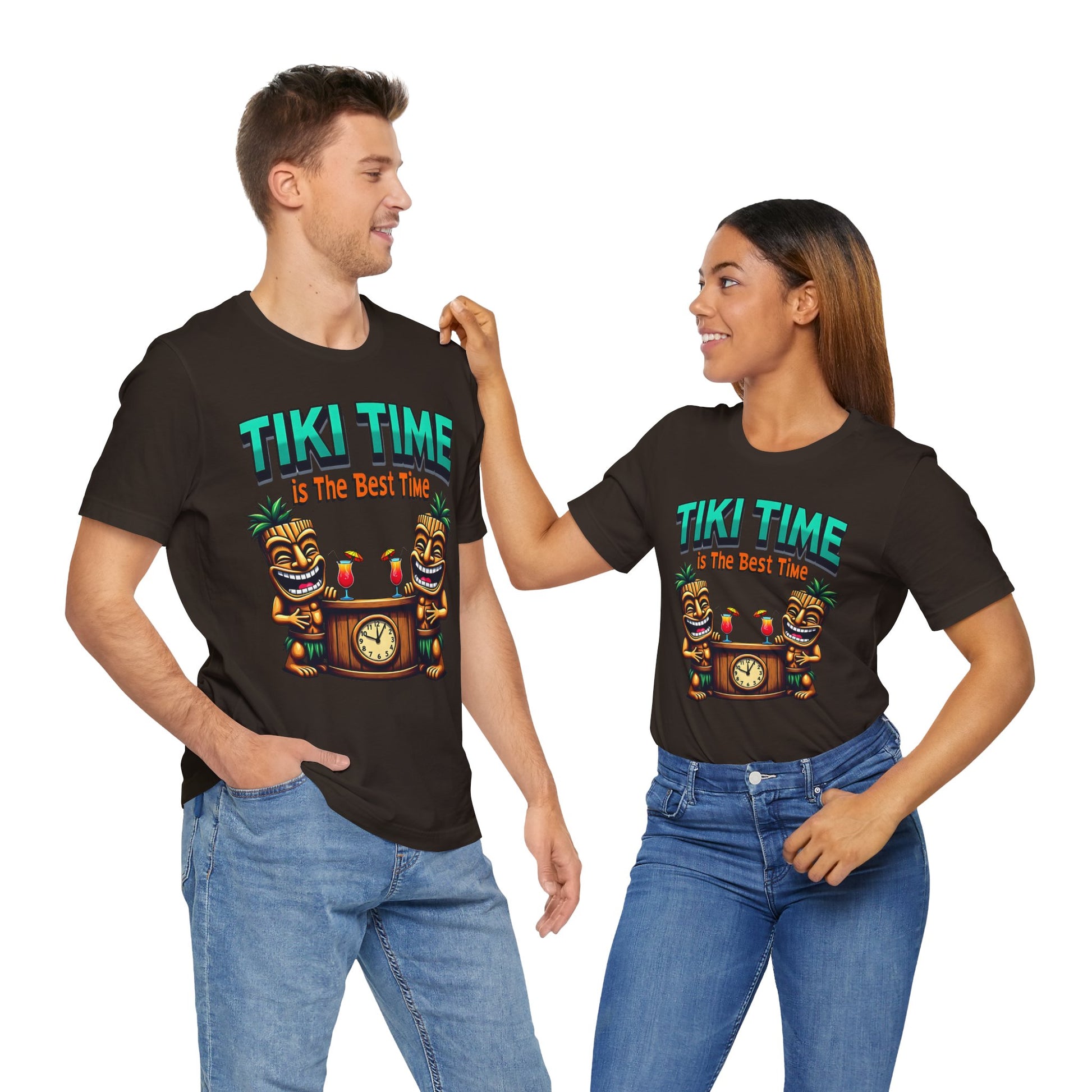 A man and woman smile at each other, both wearing the Tiki Time Unisex Jersey T-Shirt—a fun tropical graphic tee for beach lovers featuring vibrant colors and a clock. The woman rests her hand on the mans shoulder.