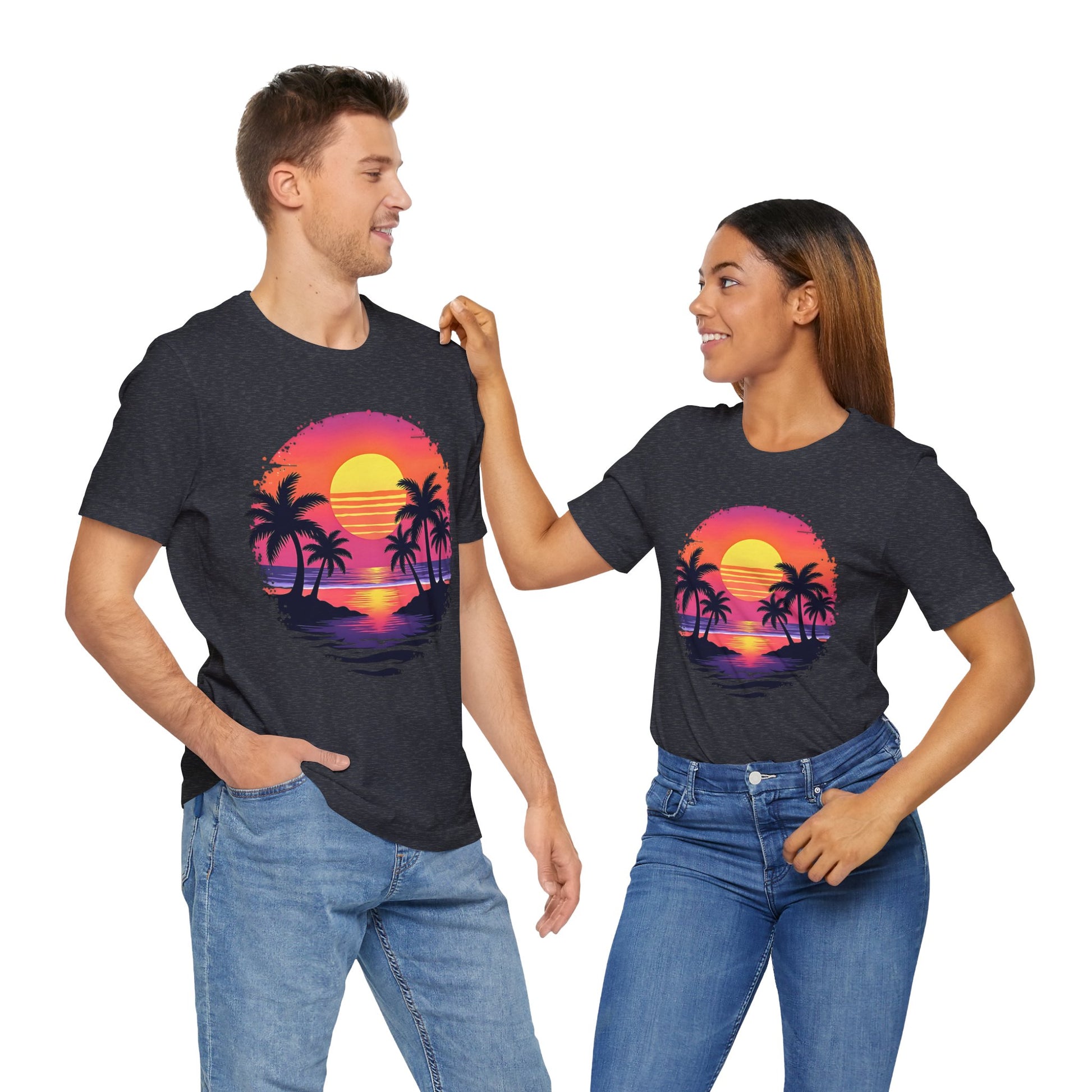 A man and woman wearing matching Tropical Sunset Graphic T-Shirt - Unisex Jersey Short Sleeve Shirt for Summer Vibes stand side by side, smiling at each other and radiating a fun, beachy vibe.