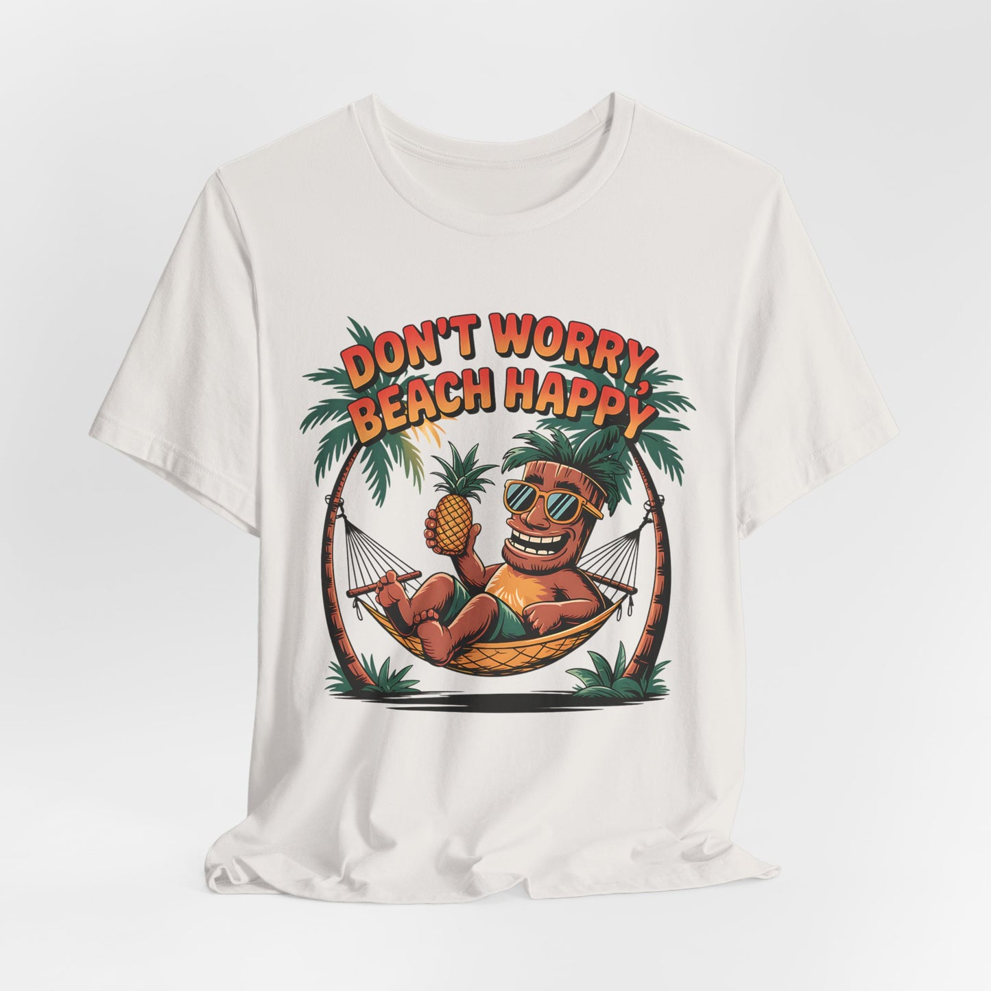 The Dont Worry Beach Happy Tiki T-Shirt is a relaxed unisex jersey tee for summer vibes, featuring a cartoon tiki in a hammock between palm trees and bold, colorful Don’t worry, beach happy text—ideal for beach lovers.