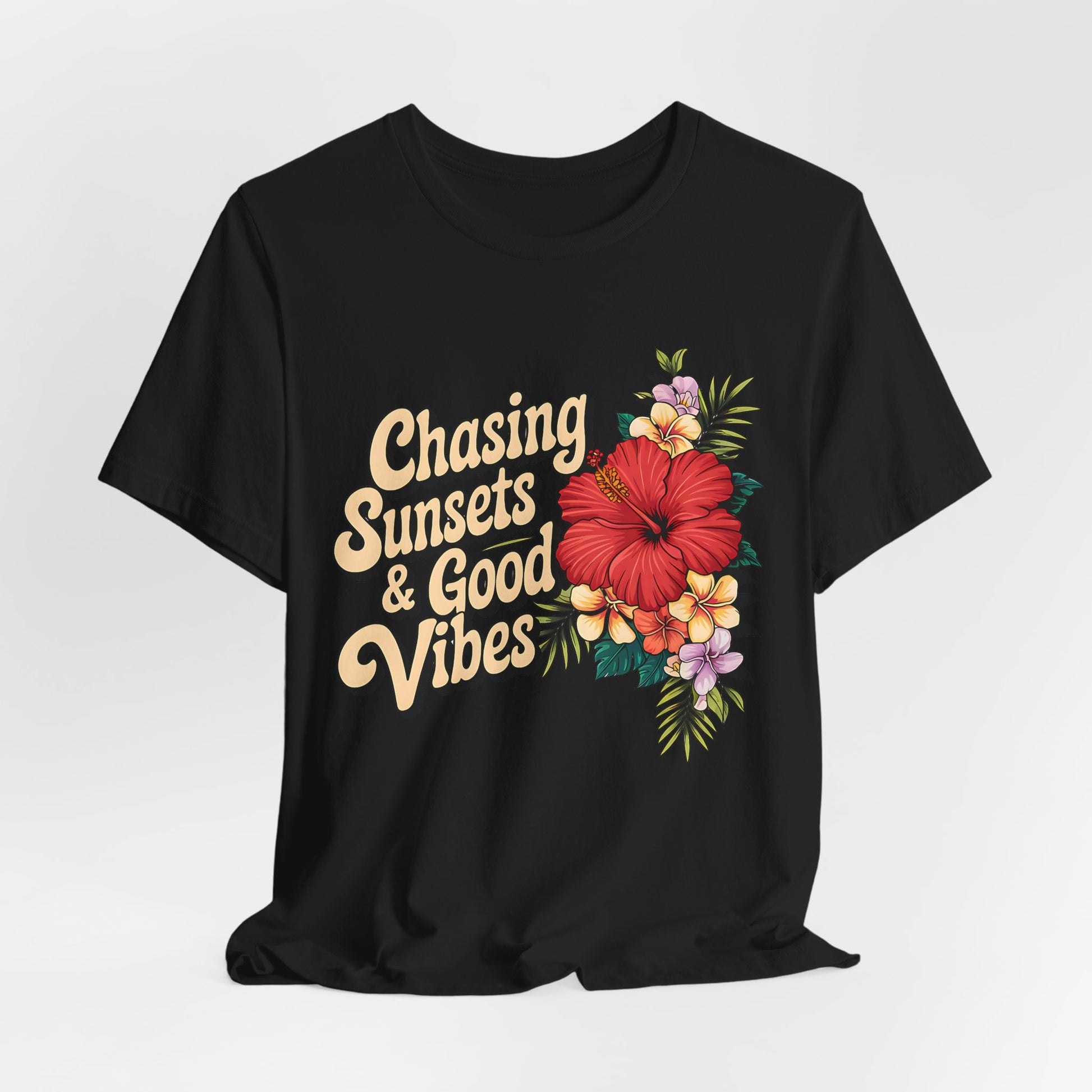 The Chasing Sunsets & Good Vibes Tee is a unisex black jersey short sleeve shirt for summer adventures, featuring retro yellow text and a floral design with vibrant red, yellow, pink, and white flowers plus green leaves.