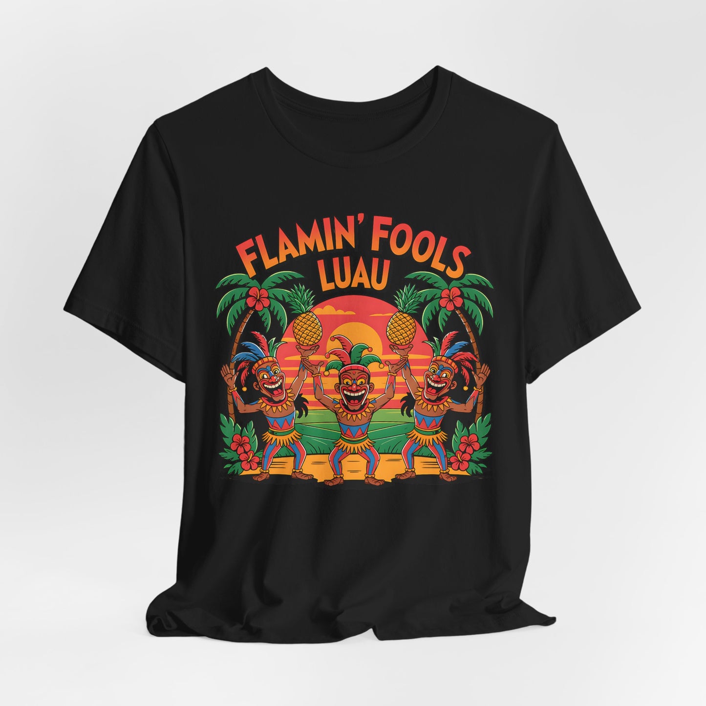 The Flamin Fools Luau Tiki T-Shirt is a black unisex jersey tee with a vibrant design of dancing tiki figures, pineapples, palm trees, and a sunset, plus FLAMIN FOOLS LUAU above the scene—perfect for beach parties.