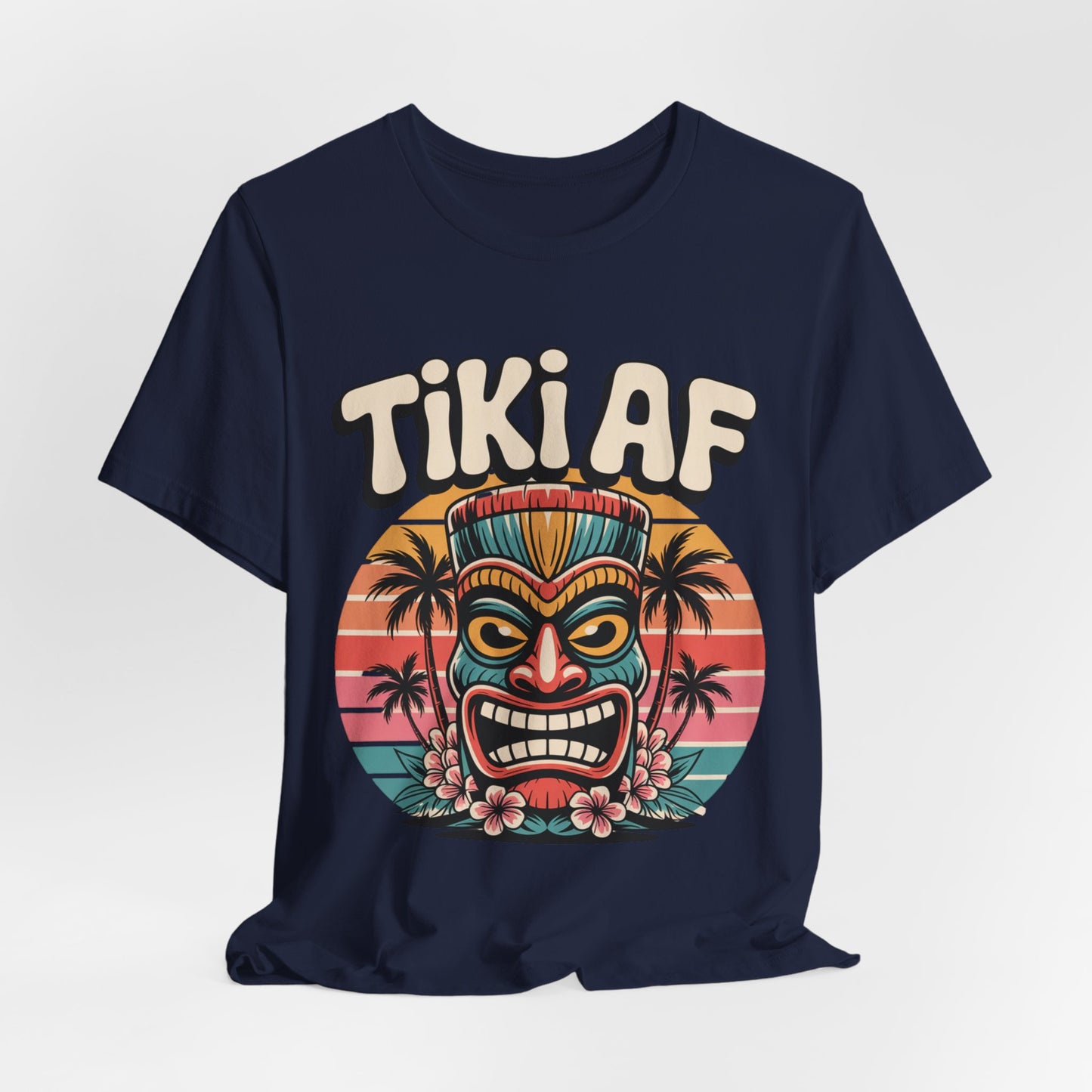 The Tiki AF Unisex Jersey Short Sleeve Tiki T-Shirt features a navy blue design with a vibrant tiki mask, sunset, palm trees, and flowers—bold retro “TIKI AF” lettering makes it the perfect tropical vibe tee for all beach lovers.