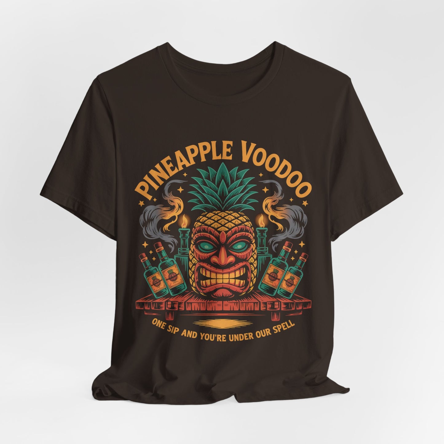 The Pineapple Voodoo Tiki T-Shirt is a black unisex jersey featuring a vibrant tiki mask with pineapple top, surrounded by bottles and smoke. “Pineapple Voodoo” is above, “One sip and you’re under our spell” below. Perfect for beach lovers!.