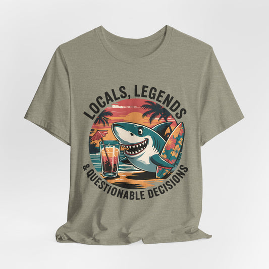 Ideal for beach lovers or summer festivals, the Funny Shark Graphic T-Shirt features a cartoon shark with a surfboard and cocktail at sunset, plus bold LOCALS, LEGENDS & QUESTIONABLE DECISIONS text. Unisex jersey short sleeve style.