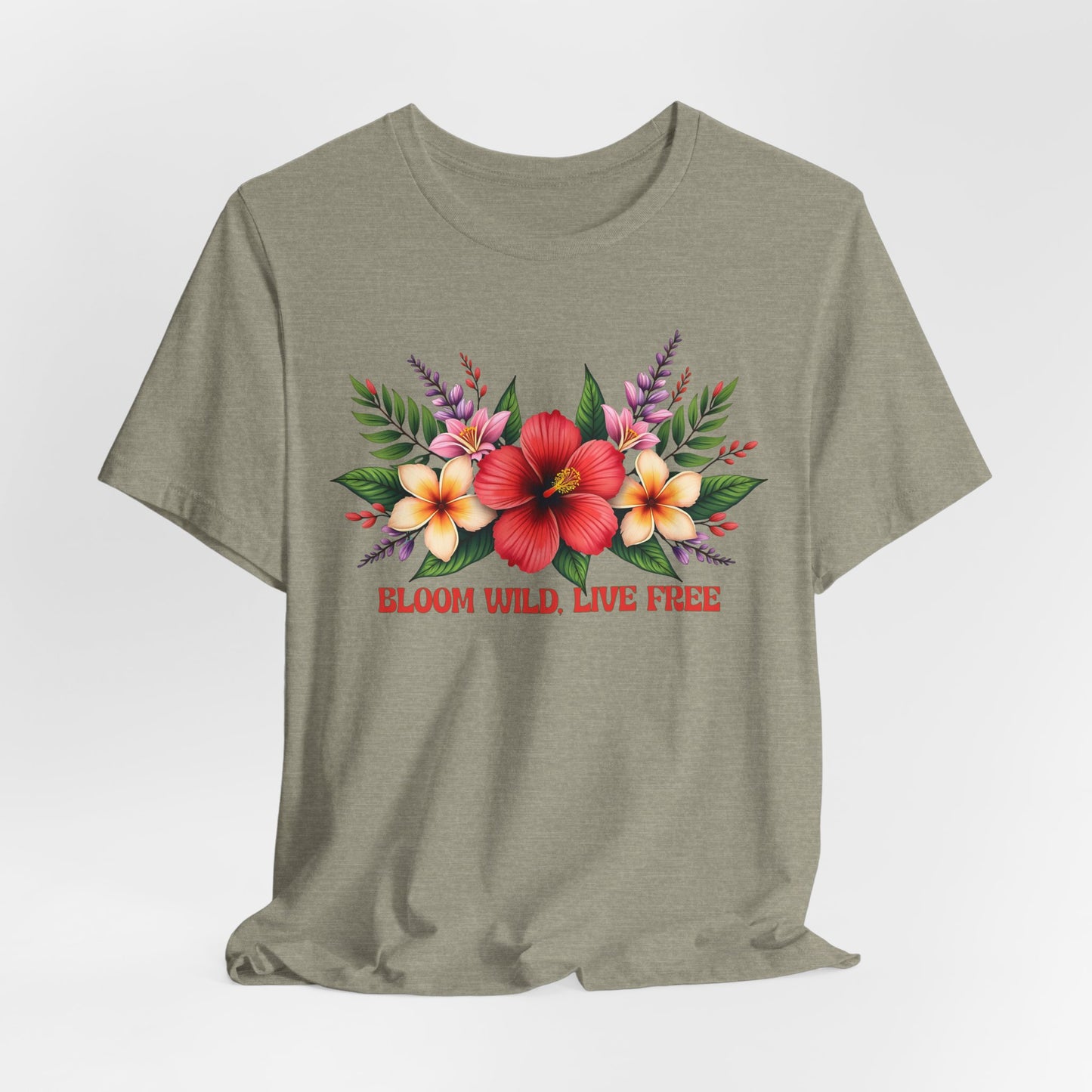 The Bloom Wild, Live Free Floral Tee is a light olive green unisex jersey short sleeve shirt with a vibrant floral design and green leaves on the chest, plus BLOOM WILD, LIVE FREE in red beneath the flowers.