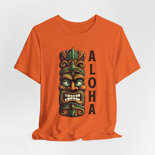 The Aloha Tiki- Graphic Tiki T-Shirt for Beach Lovers is an orange unisex tee with a bold tiki mask and ALOHA graphic, perfect for anyone who loves tropical vibes and beach adventures.