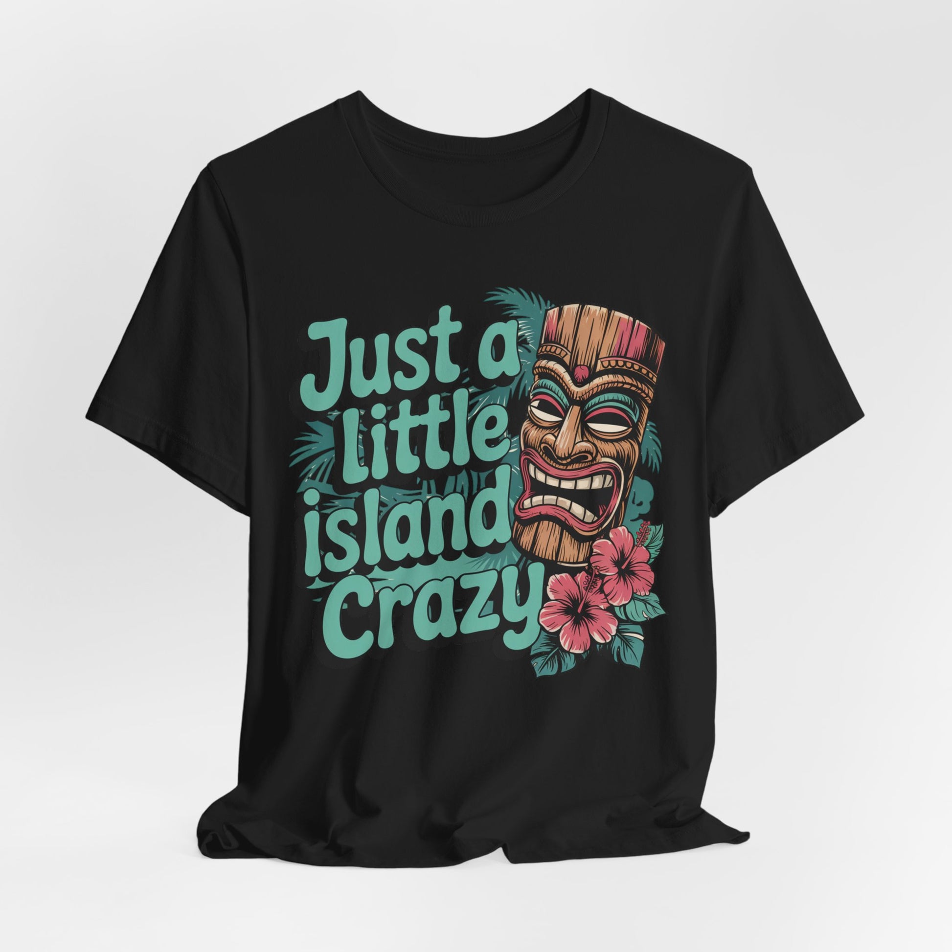 The Tiki Island Crazy Unisex Tiki T-Shirt features vibrant tiki mask art, pink hibiscus, green leaves, and bold Just a Little Island Crazy text—perfect for tropical vibes and fans of island culture.