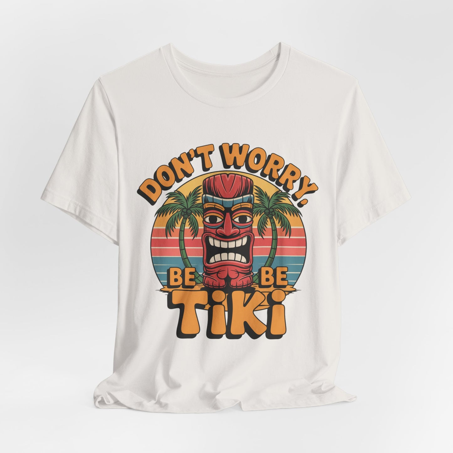 The Tiki Vibes Unisex Jersey Tiki T-Shirt features a vibrant red tiki mask, palm trees, sunset, and bold “DONT WORRY, BE TIKI” text—a playful graphic shirt perfect for any casual wardrobe.