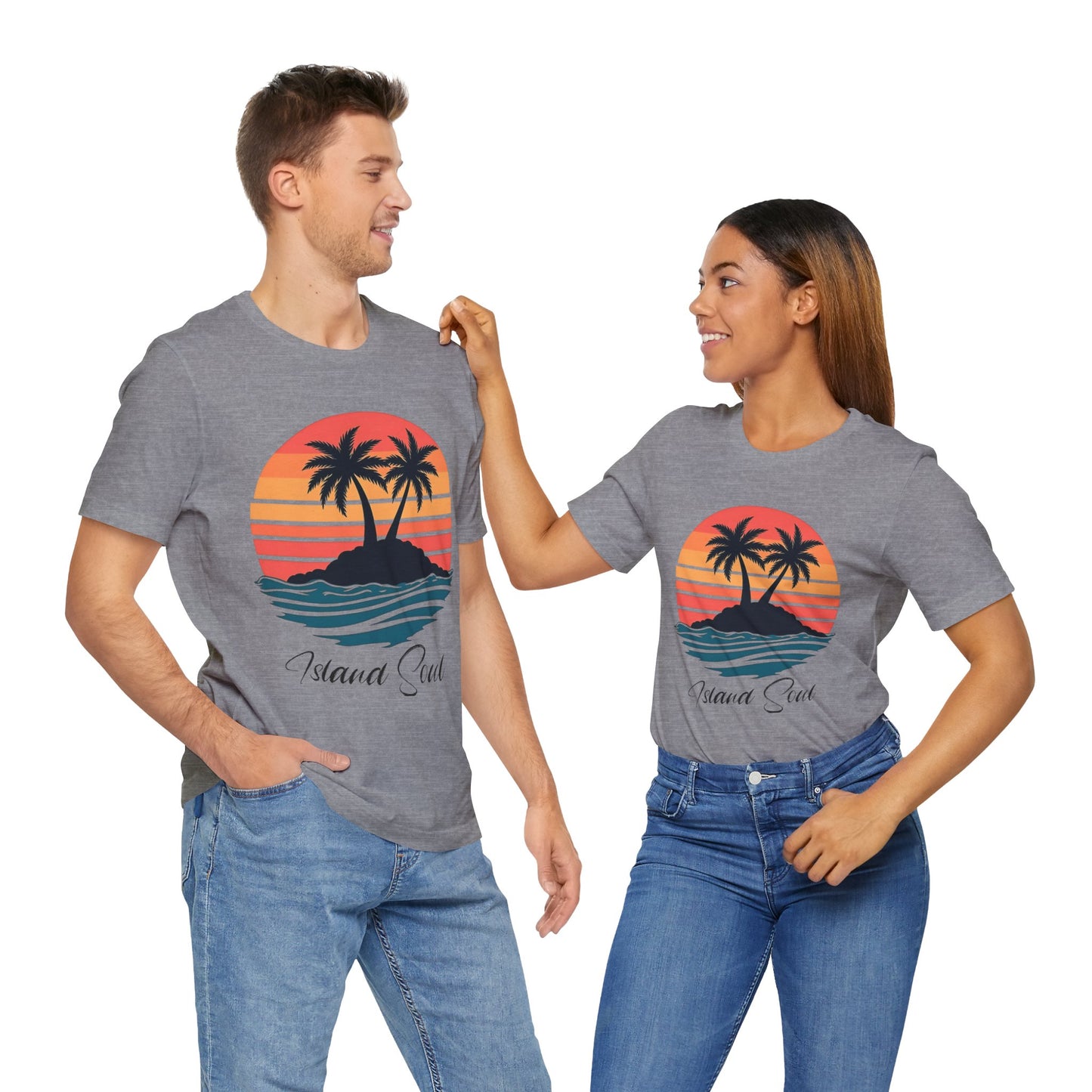 A man and woman in blue jeans relax together in matching Island Soul Unisex T-Shirts—Retro Sunset Tee with palm trees—smiling and capturing laid-back island vibes against a clean white background.