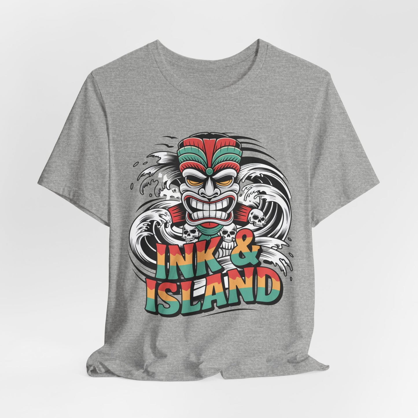 The Tropical Ink & Island Unisex Tiki T-Shirt features a vibrant cartoon tiki mask and bold waves with INK & ISLAND text—a stylish summer essential for beachwear and island culture lovers.