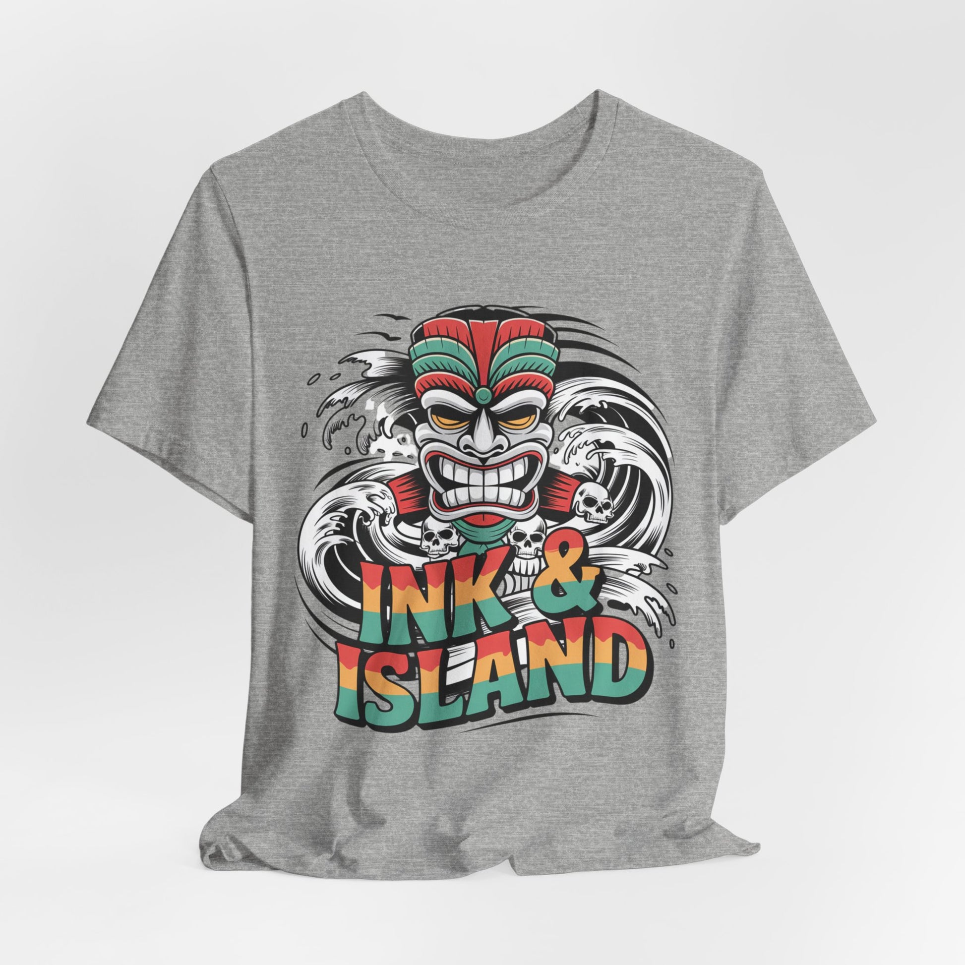 The Tropical Ink & Island Unisex Tiki T-Shirt features a vibrant cartoon tiki mask and bold waves with INK & ISLAND text—a stylish summer essential for beachwear and island culture lovers.