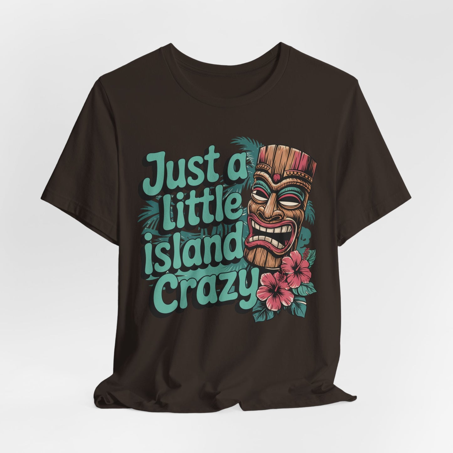 The Tiki Island Crazy Unisex Tiki T-Shirt features a vibrant tiki mask, pink hibiscus flowers, and teal “Just a little island crazy” text—perfect for showcasing lively tropical vibes and fun island culture.