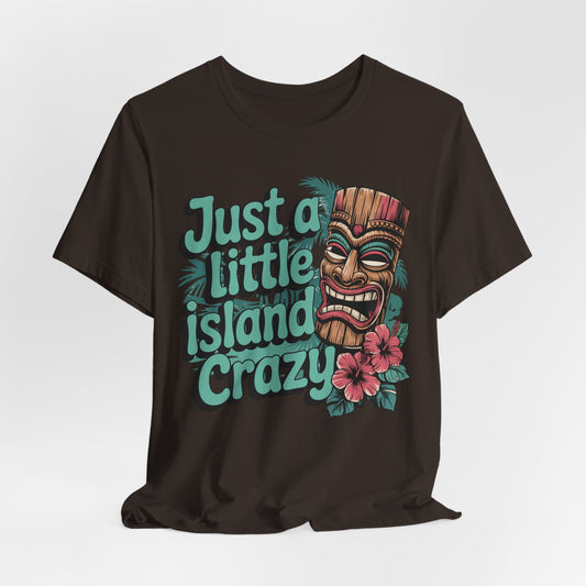 The Tiki Island Crazy Unisex Tiki T-Shirt features a vibrant tiki mask, pink hibiscus flowers, and teal “Just a little island crazy” text—perfect for showcasing lively tropical vibes and fun island culture.
