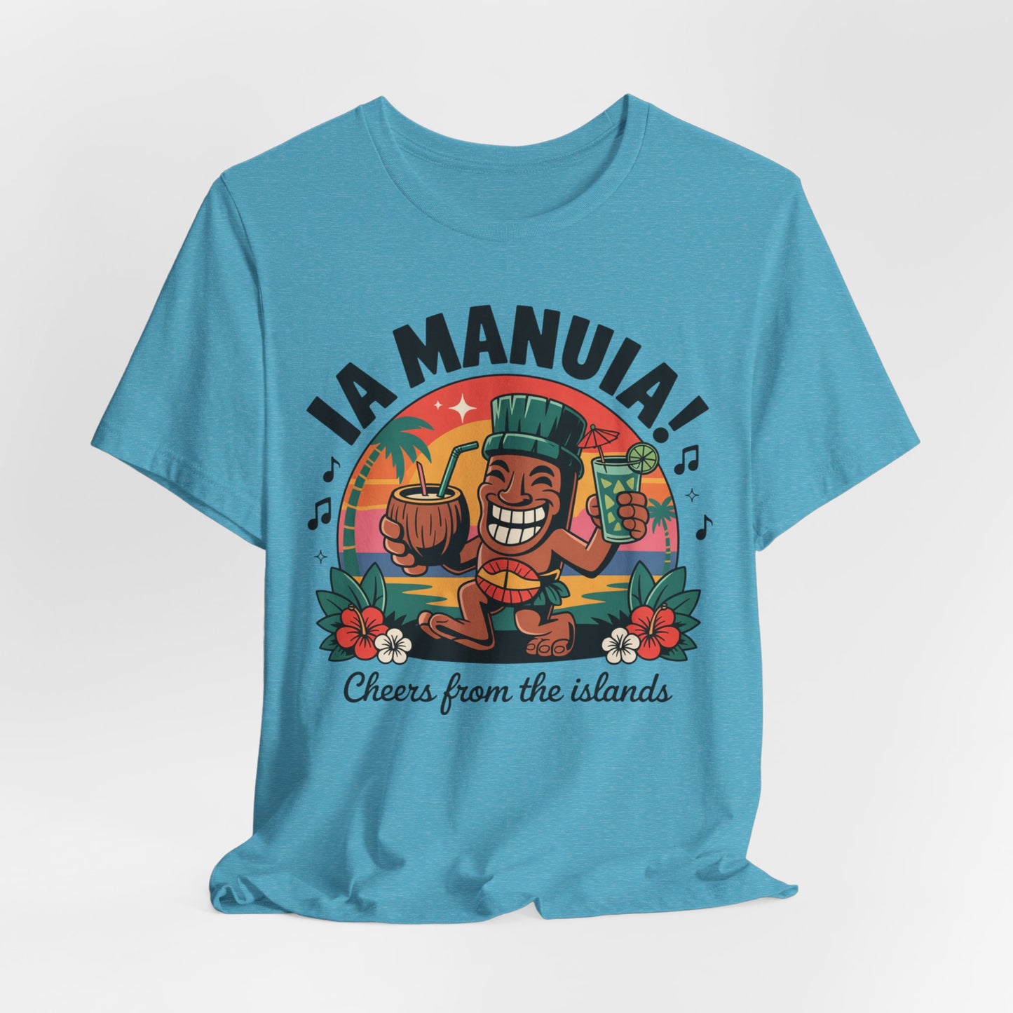 The IA MANUIA! Island Vibes Unisex Jersey Tiki T-Shirt in blue features a smiling cartoon tiki, tropical drinks, flowers, palm trees, and a sunset. Breathable cotton—perfect for island-themed events. Text: “IA MANUIA! Cheers from the islands.”.