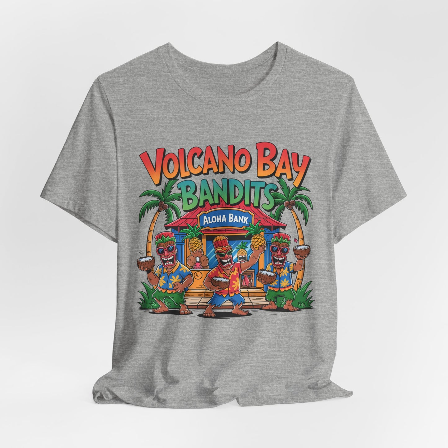 The Volcano Bay Bandits Graphic Tiki T-Shirt is a gray unisex short sleeve shirt featuring three cartoon tiki characters dancing by a tropical Aloha Bank, with palm trees, and the text Volcano Bay Bandits in colorful print.