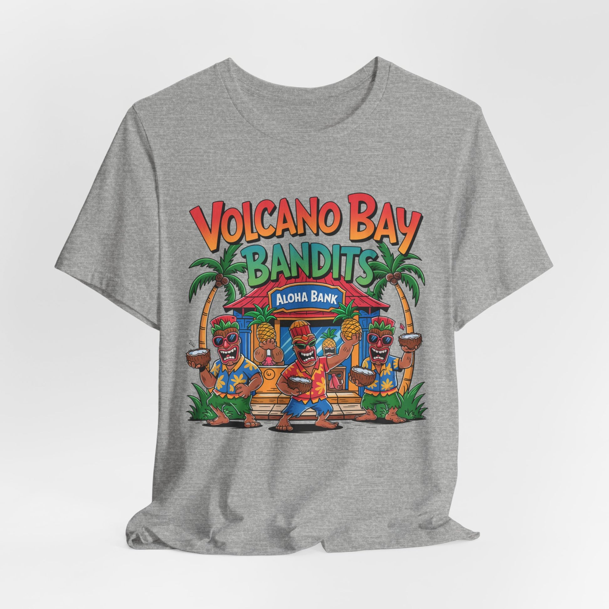 The Volcano Bay Bandits Graphic Tiki T-Shirt is a gray unisex short sleeve shirt featuring three cartoon tiki characters dancing by a tropical Aloha Bank, with palm trees, and the text Volcano Bay Bandits in colorful print.