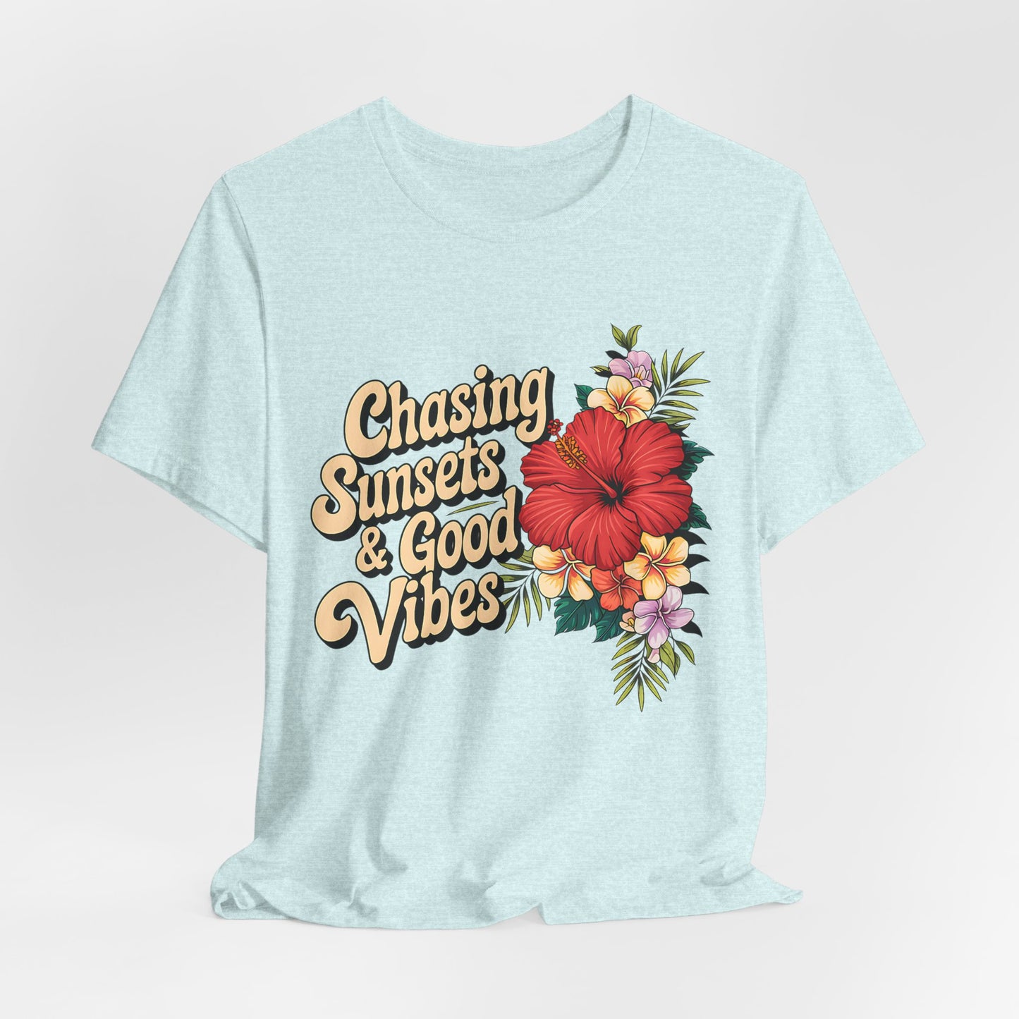 The Chasing Sunsets & Good Vibes Tee is a light blue unisex jersey shirt for summer adventures, featuring a retro design with vibrant hibiscus and florals for a carefree spirit.