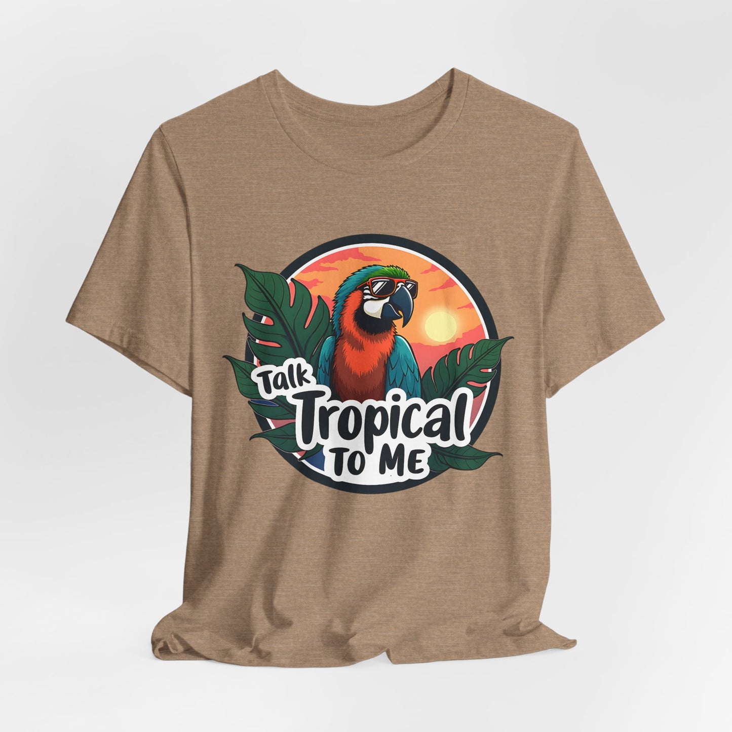 The Tropical Parrot Tee - Talk Tropical to Me Unisex Jersey Short Sleeve Shirt features a vibrant parrot in sunglasses, lush green leaves, a sunset backdrop, and playful text for the ultimate tropical vibes.