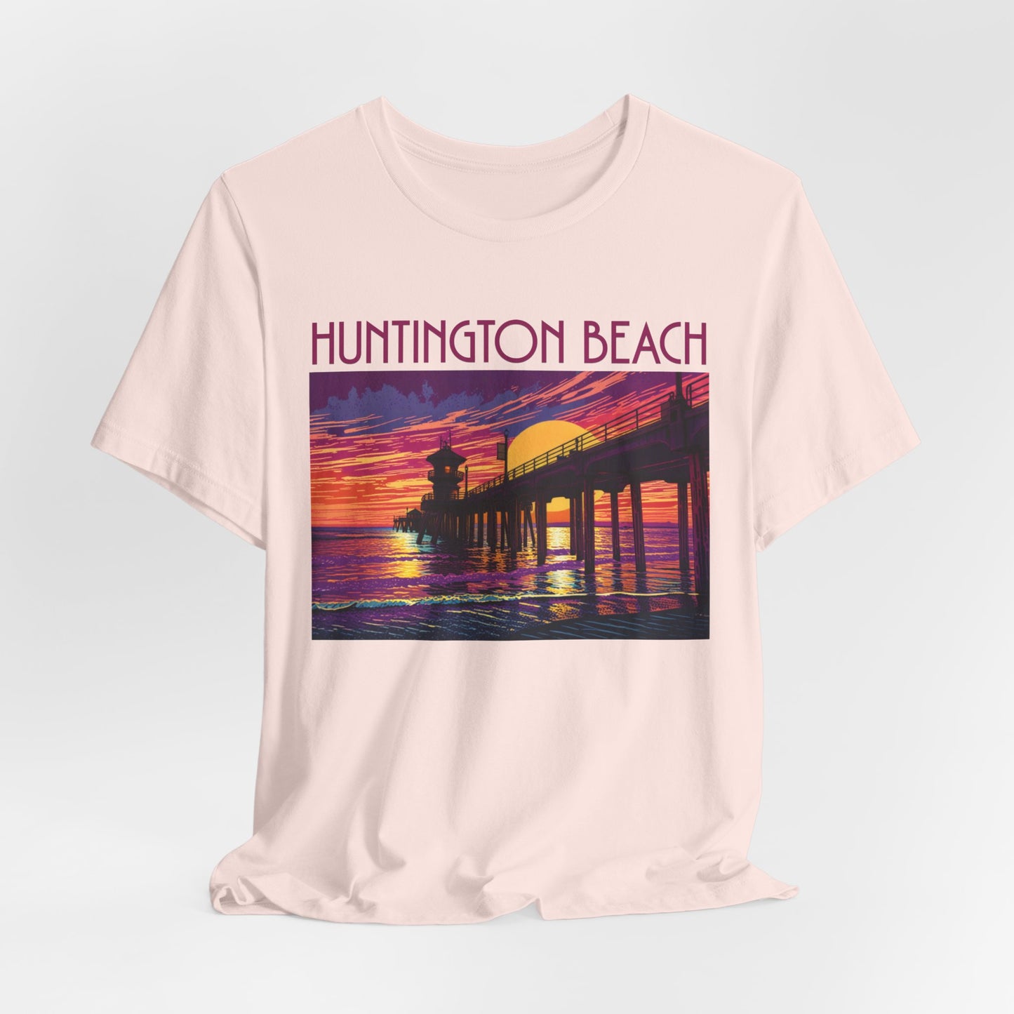 The Huntington Beach Sunset T-Shirt - Unisex Jersey Short Sleeve features a vibrant pier-at-sunset illustration with purple, orange, and yellow hues, plus bold red “Huntington Beach” text—a stylish tribute to beach culture.