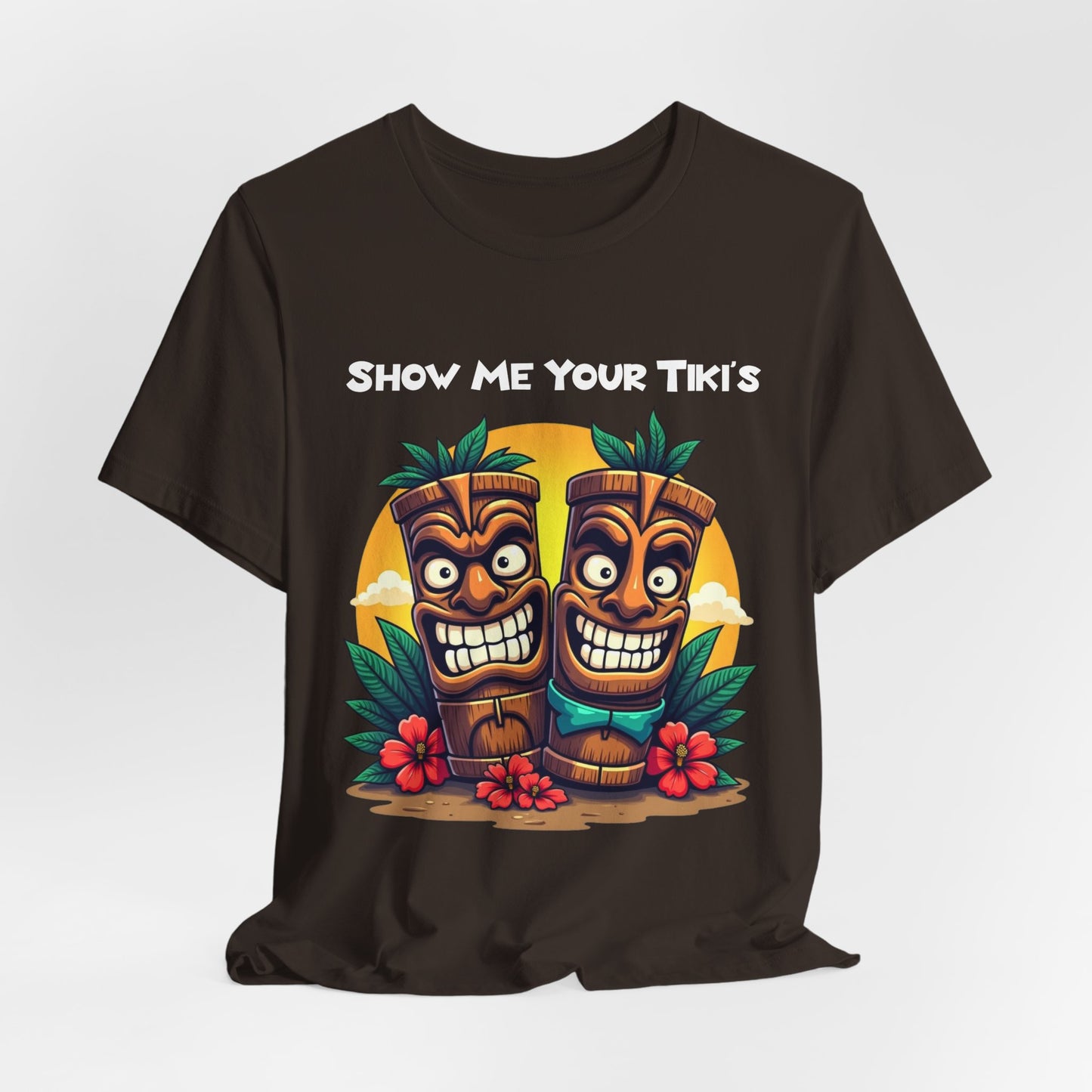The Tiki Fun Unisex Jersey Short Sleeve Tiki T-Shirt features a vibrant tropical graphic with two smiling tikis, lush leaves, red hibiscus flowers, and SHOW ME YOUR TIKIS—crafted from soft Airlume cotton for comfort.