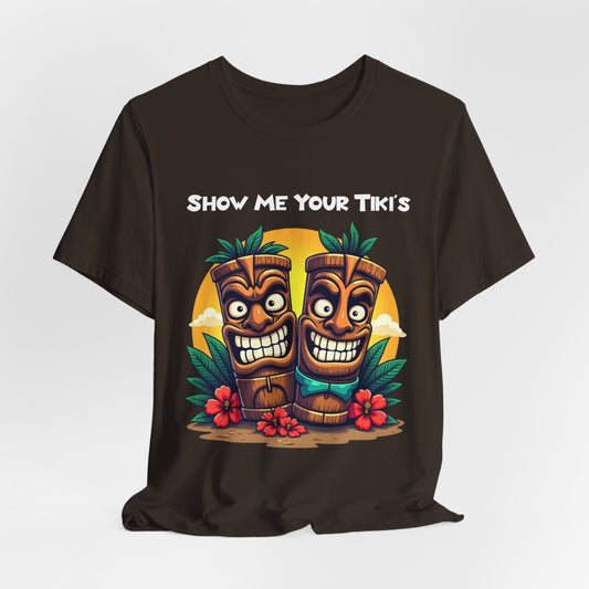 The Tiki Fun Unisex Jersey Short Sleeve Tiki T-Shirt features a vibrant tropical graphic with two smiling tikis, lush leaves, red hibiscus flowers, and SHOW ME YOUR TIKIS—crafted from soft Airlume cotton for comfort.