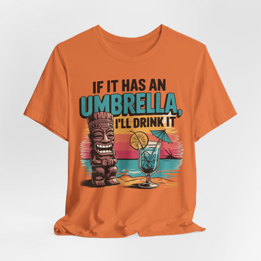 The Tropical Fun Tiki T-Shirt features a tiki figure, tropical cocktail with an umbrella, and the text If It Has an Umbrella, Ill Drink It on an orange tee with a beach sunset background for ultimate tropical vibes.