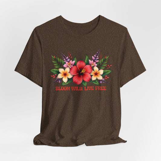The Bloom Wild, Live Free Floral Tee is a brown unisex jersey short sleeve shirt with a vibrant floral print and “BLOOM WILD, LIVE FREE” in red below the tropical flowers and green leaves.