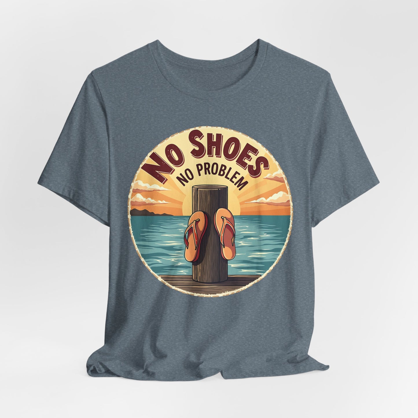 The Unisex No Shoes No Problem Graphic Tee is a blue shirt with sandals on a wooden post by water at sunset and “NO SHOES NO PROBLEM” above—perfect for a laid-back, casual beach vibe.