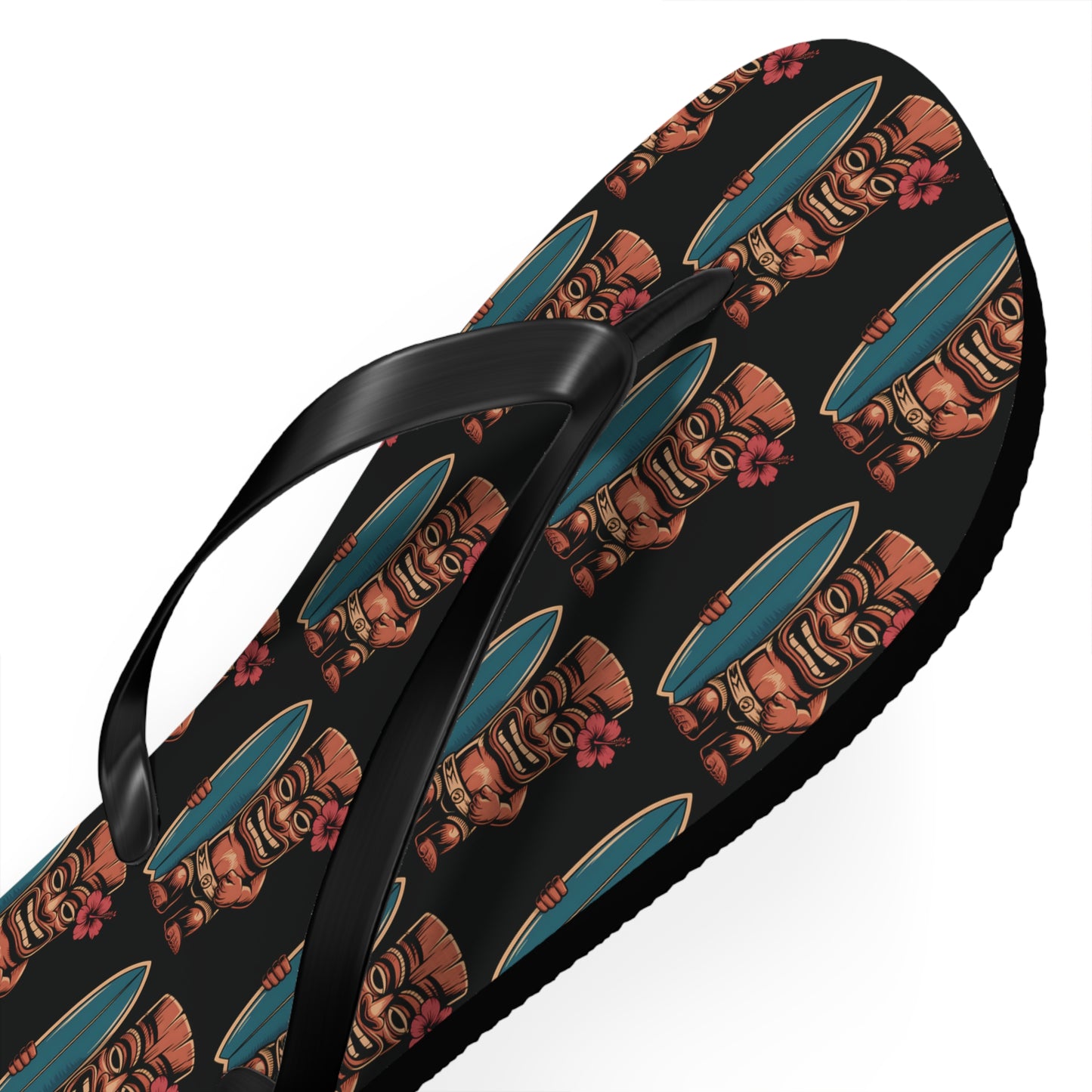 The Tiki Surf Flip Flops - Fun Summer Beach Sandals feature black polyester suede straps with colorful brown tiki masks in teal helmets and red flowers, creating a tropical, playful vibe—perfect for summer fun at the beach.
