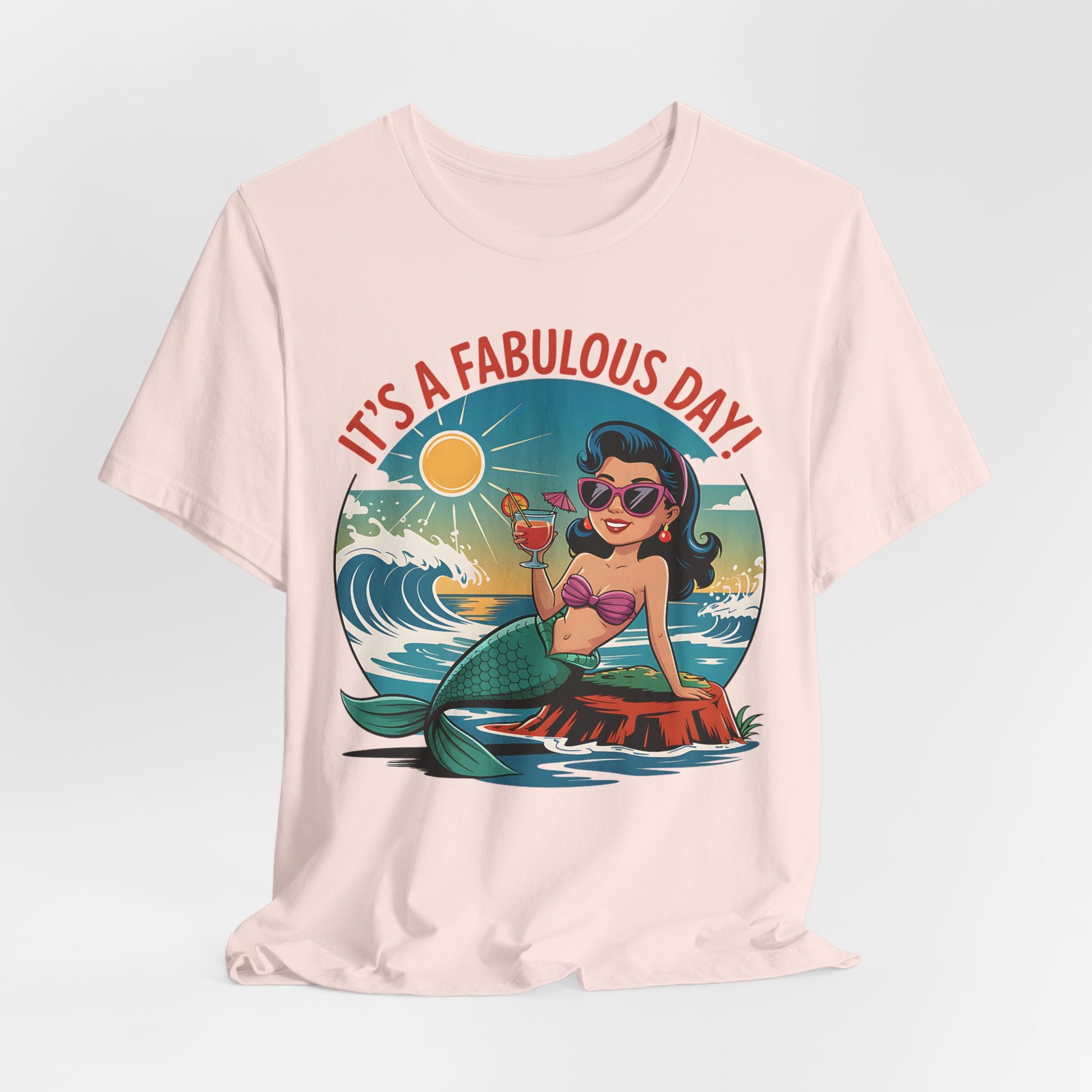 The Fabulous Day Mermaid Unisex Tee is a light pink jersey featuring a cartoon mermaid with sunglasses and ice cream by the ocean, plus “IT’S A FABULOUS DAY!” in bold red—perfect for fantasy-themed events.