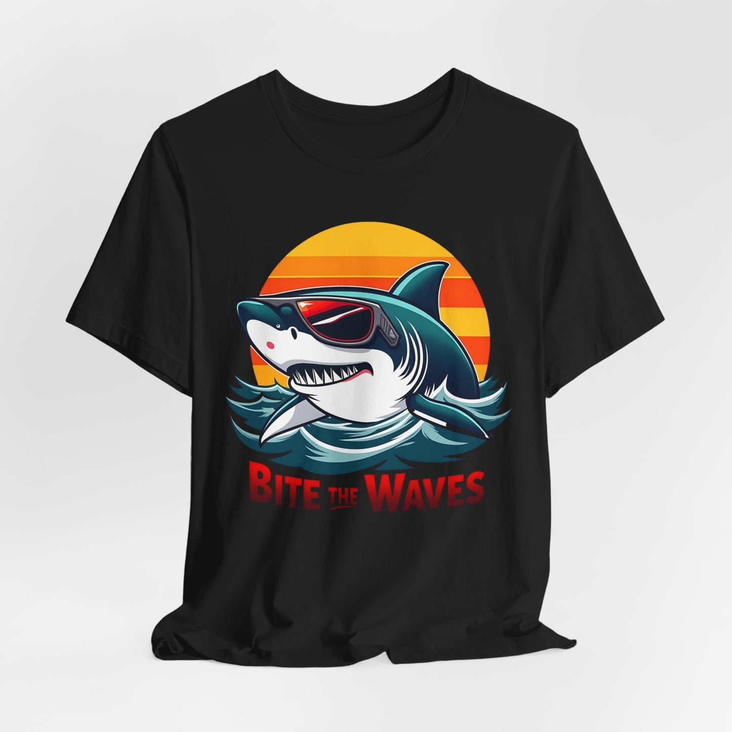 The Bite the Waves Shark T-Shirt is a black unisex jersey featuring a cartoon shark in sunglasses, emerging from water with a sunset. Bite the Waves appears in bold red letters, making it perfect for beach vacations.
