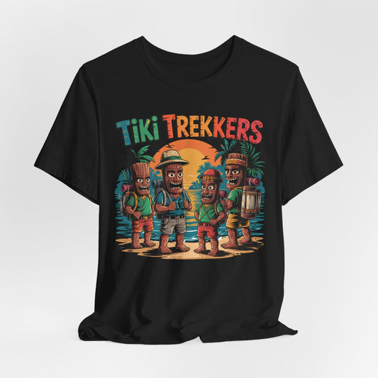 The Tiki Trekkers Graphic Unisex Jersey T-Shirt features four cartoon tikis in explorer outfits on a sunset beach with palm trees and colorful Tiki Trekkers text—perfect for outdoor and adventure lovers.