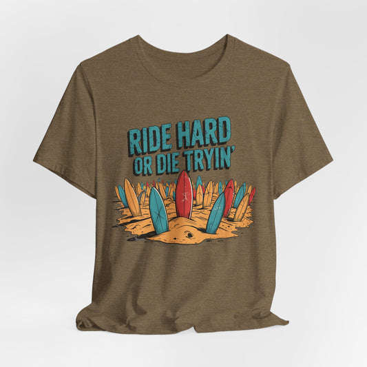 The Surfing T-Shirt - Ride Hard or Die Tryin Unisex Jersey features an olive green, short sleeve design with illustrated surfboards in sand and “RIDE HARD OR DIE TRYIN’” in bold blue and white above the boards.