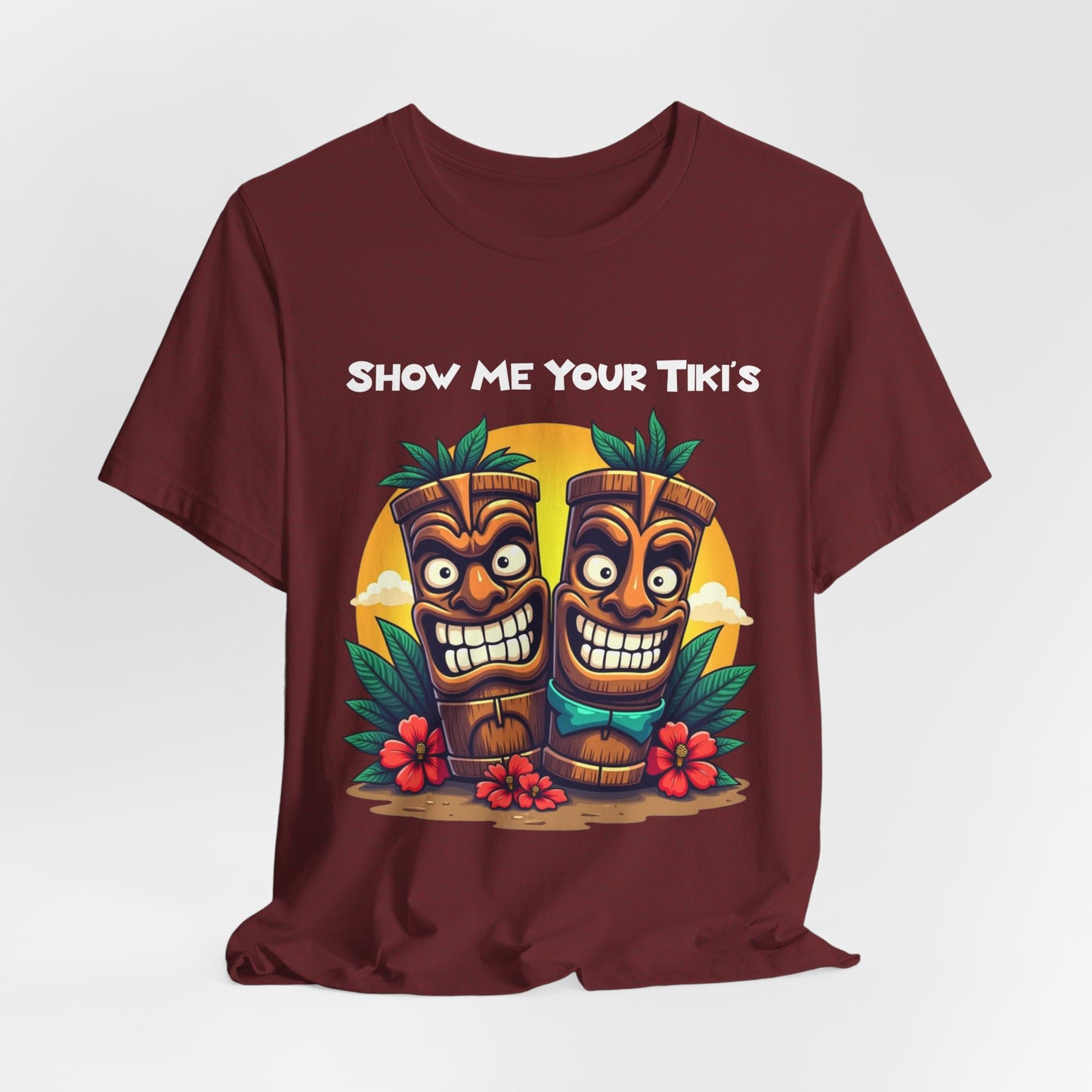 The Tiki Fun Unisex Jersey Short Sleeve Tiki T-Shirt features smiling tiki statues, lush leaves, red flowers, and SHOW ME YOUR TIKIS on soft Airlume cotton. A bold, tropical graphic shirt for all!.