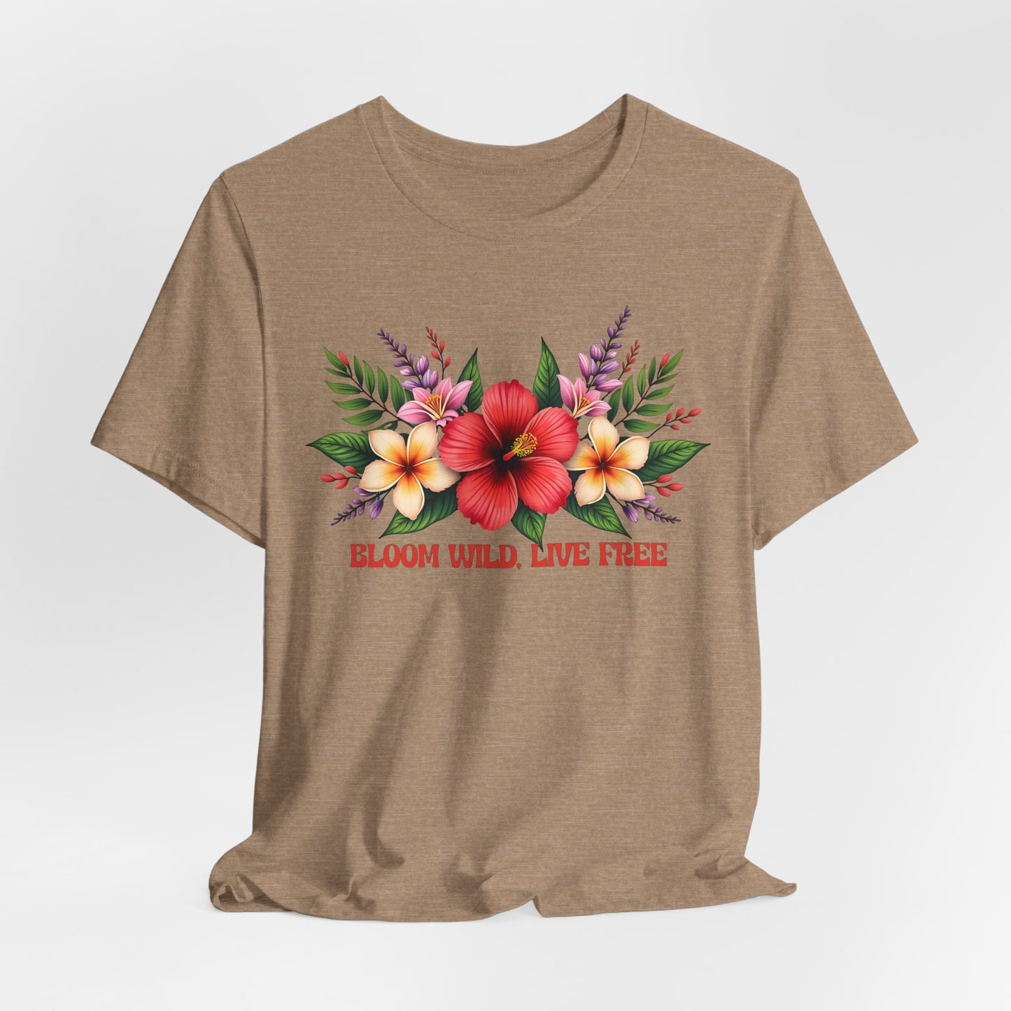 The Bloom Wild, Live Free Floral Tee - Unisex Jersey Short Sleeve T-Shirt features a tan base with vibrant red, yellow, and pink flowers plus green leaves. Made from breathable fabric; beneath the flowers it reads: BLOOM WILD, LIVE FREE.